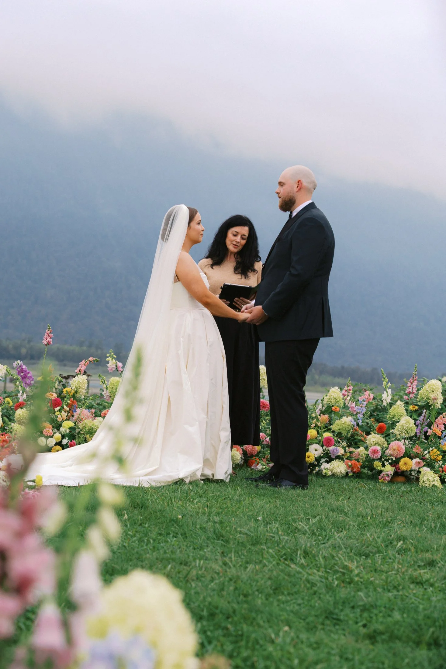Wedding ceremony at Fraser River Lodge featuring aisle entrance, vow exchange, marriage signing and aisle kiss in front of ceremony florals, photographed with hybrid digital and 35mm film.