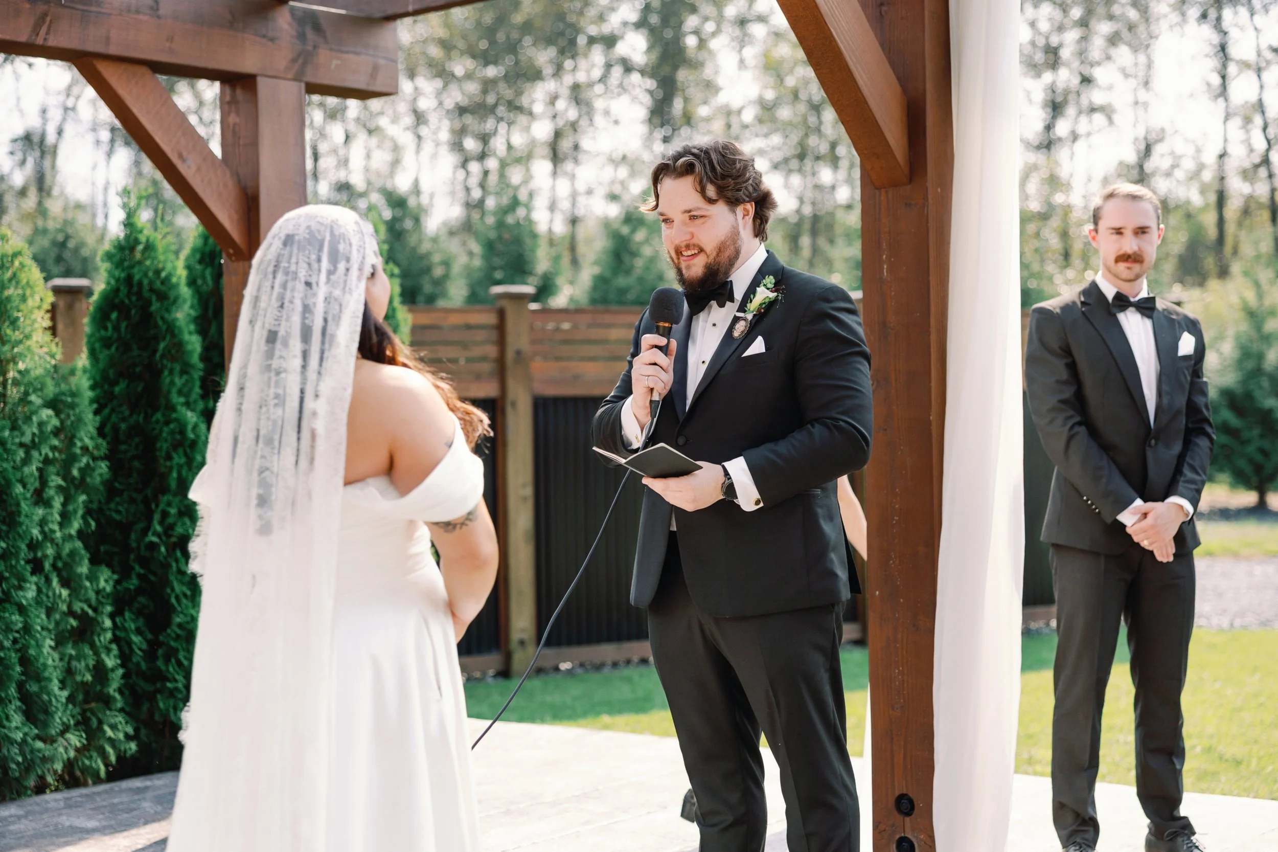 Bride and groom saying their vows beneath an elegant floral ceremony setup at a countryside Fraser Valley wedding venue.