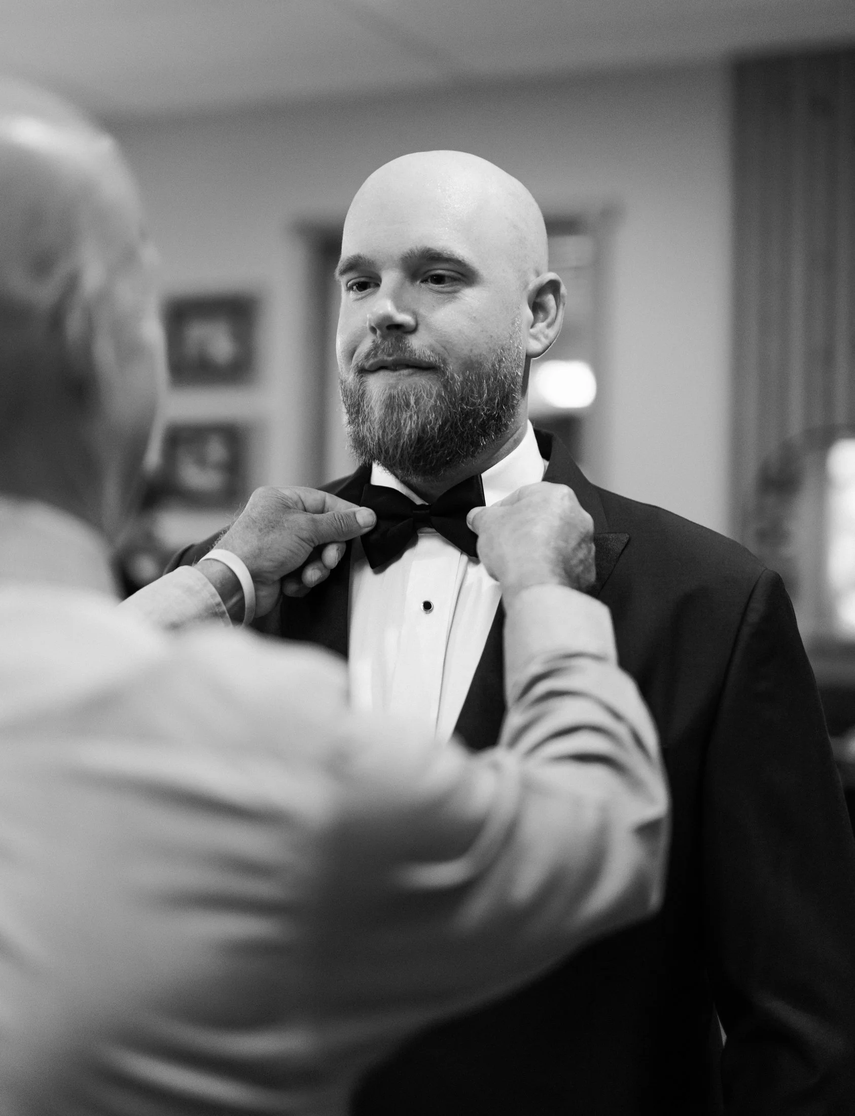 Groom putting on tie and jacket at Fraser River Lodge wedding, photographed in soft natural light with both digital and 35mm film wedding photography coverage.