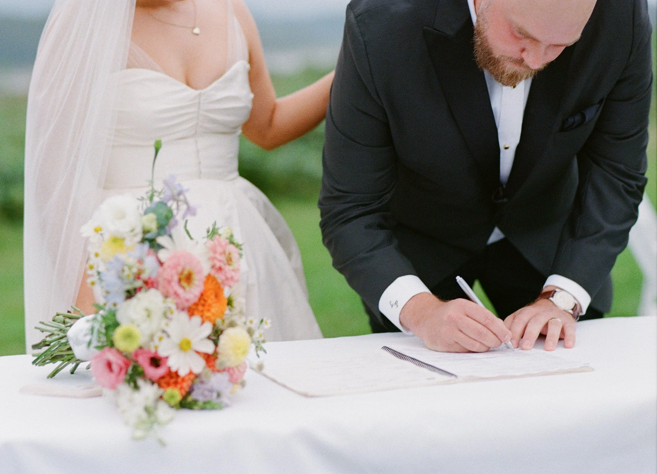 Fraser River Lodge ceremony photography with elegant outdoor decor, floral arrangement, signing table and aisle kiss, captured with timeless film wedding photography and modern digital coverage.