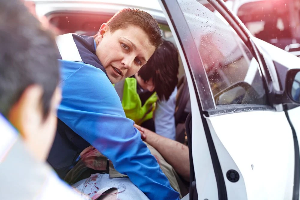 A paramedic attending a car crash, helping someone out of a car