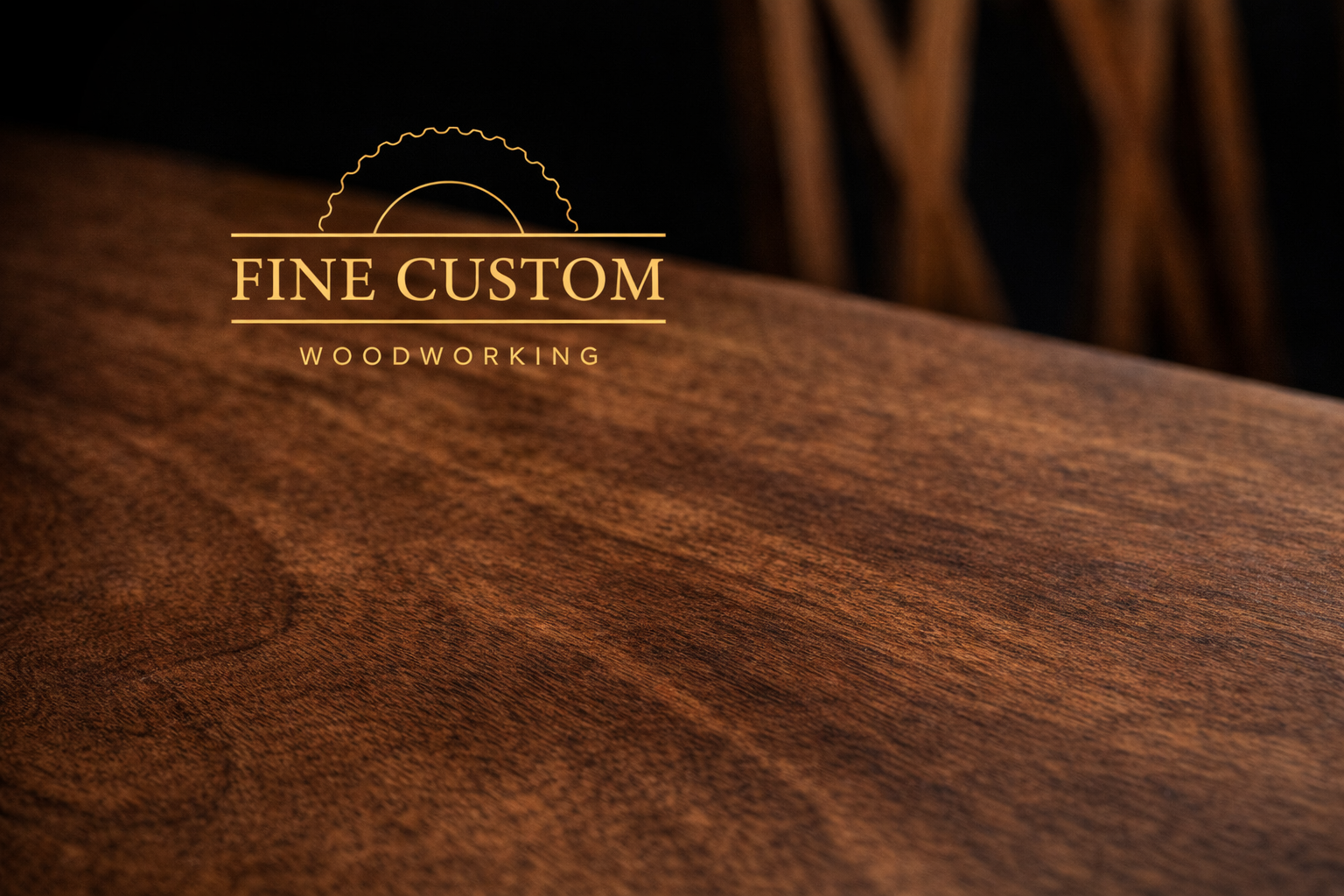 Close-up of a wooden surface with a logo that reads 'FINE CUSTOM WOODWORKING' in gold lettering.