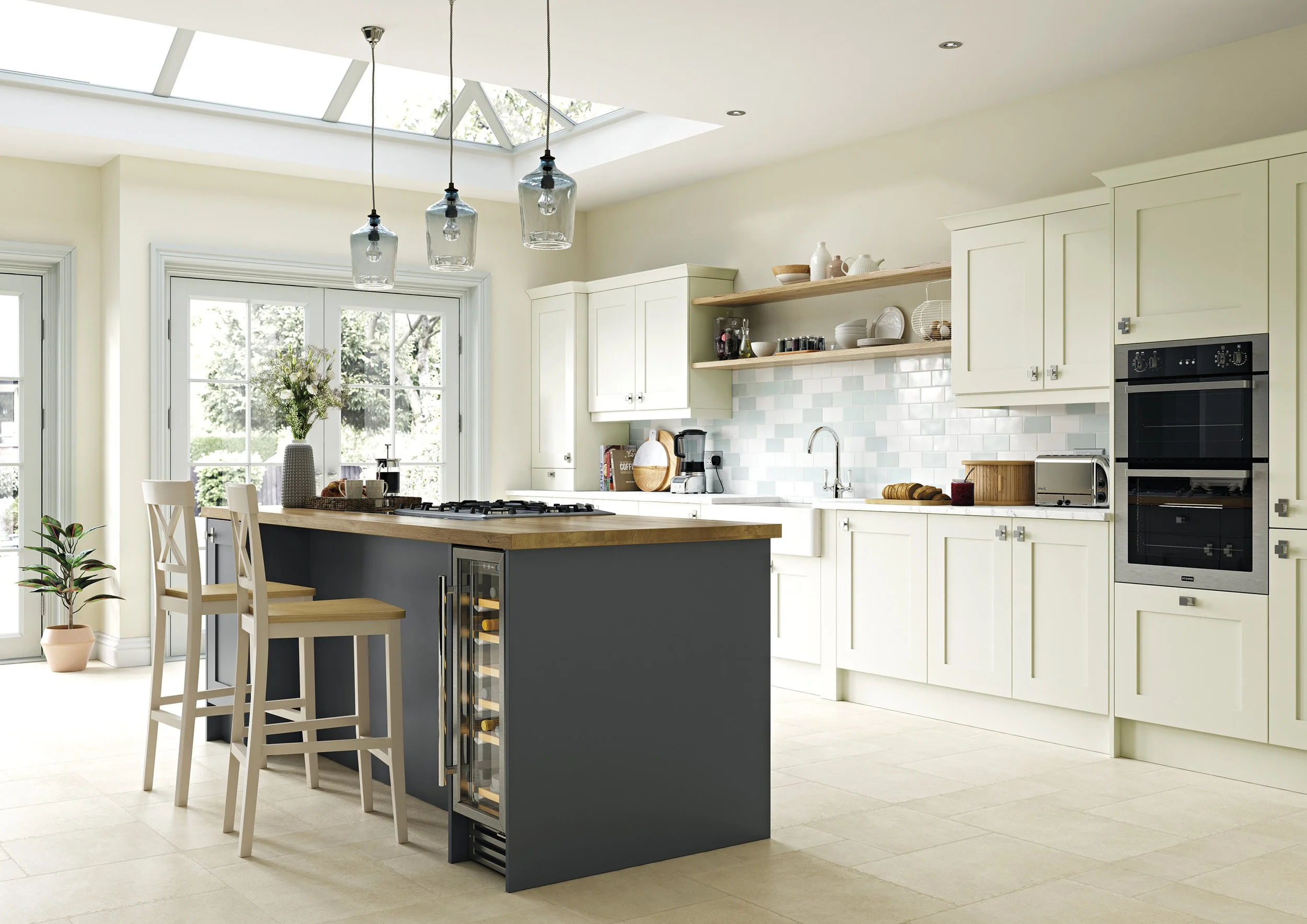 Bright kitchen with white cabinets, a skylight, a kitchen island with chair, open shelving with dishes, and a window with flowers.