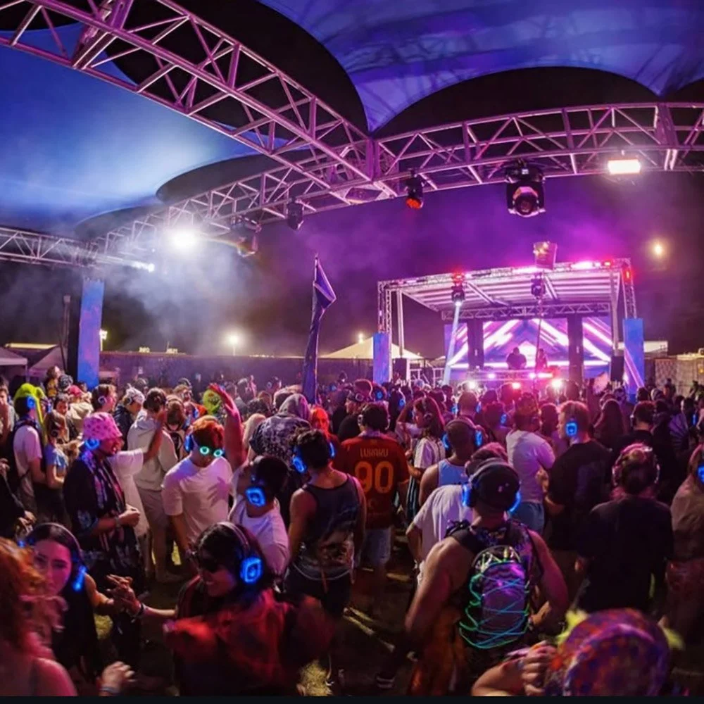 A DJ performing at a nightclub with a crowd dancing under red lighting.