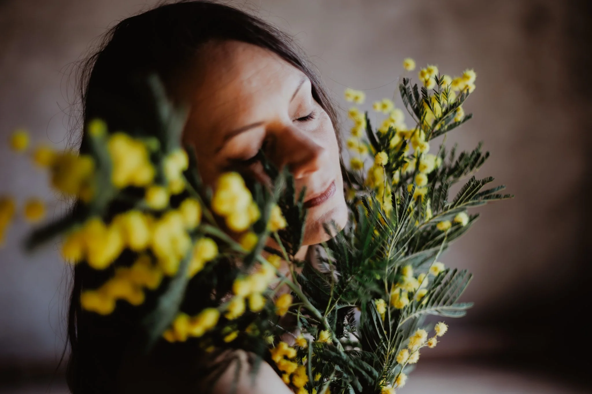 Une femme a les yeux fermés, tenant un cadran d'horloge en plein air avec une ombre du cadran visible sur son visage.