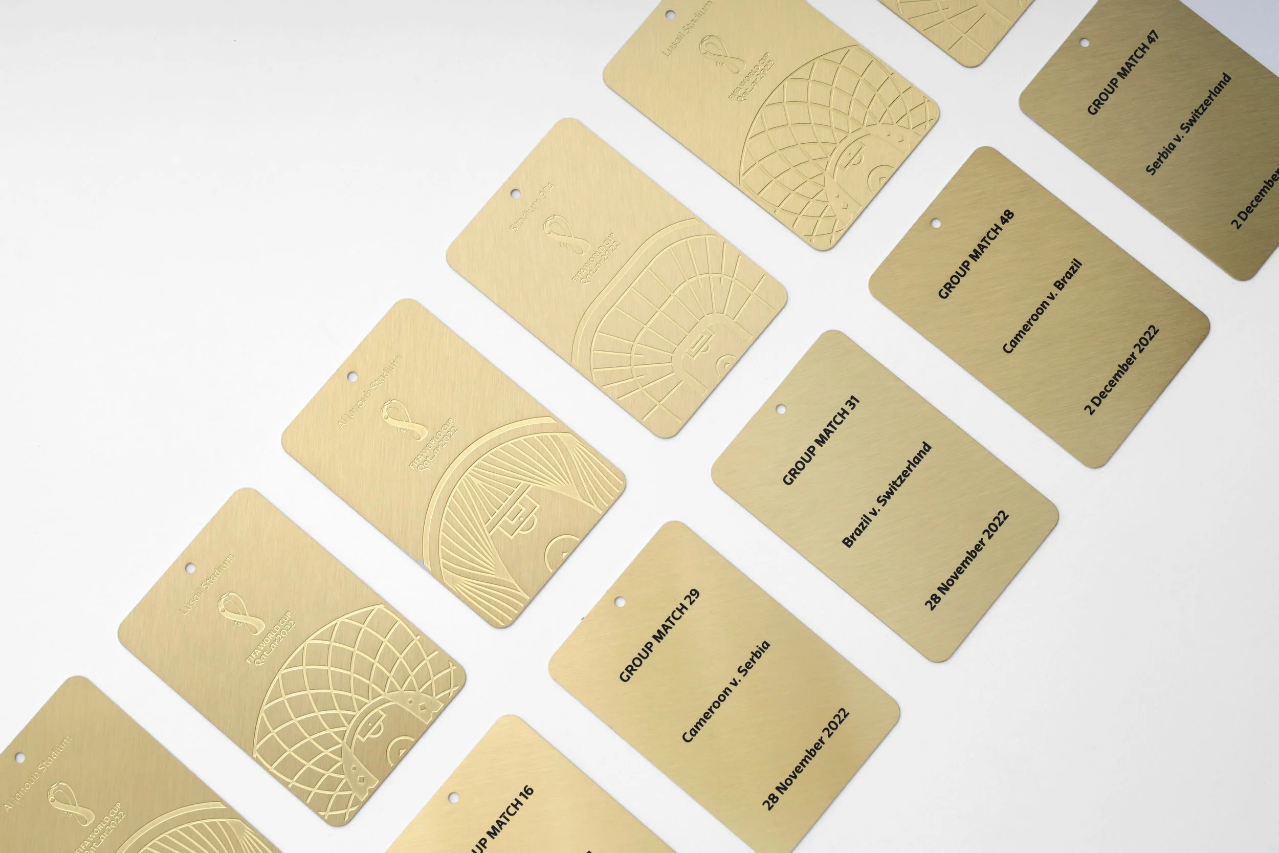 Golf tournament match cards with gold finish, each labeled with group match number, competing countries, and date, arranged on a white background.