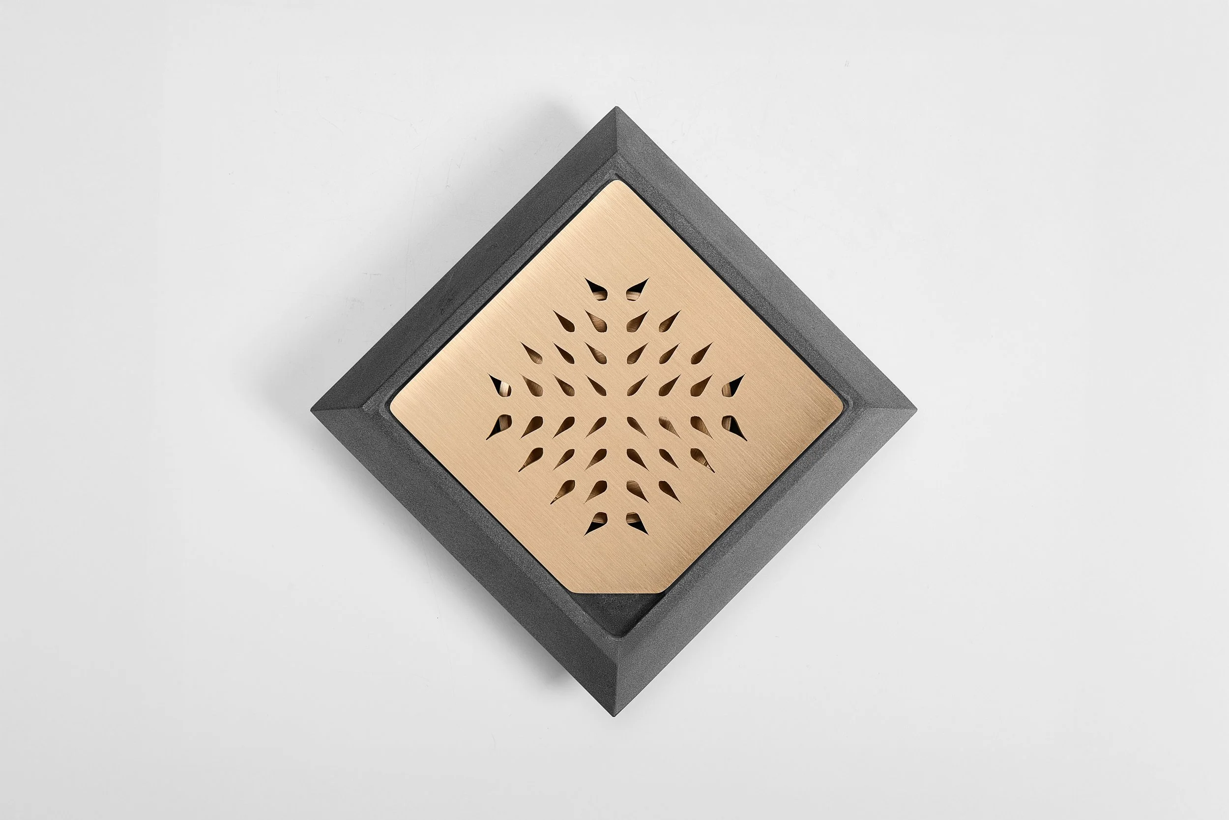 A modern wooden speaker with a geometric pattern, positioned on a white background.