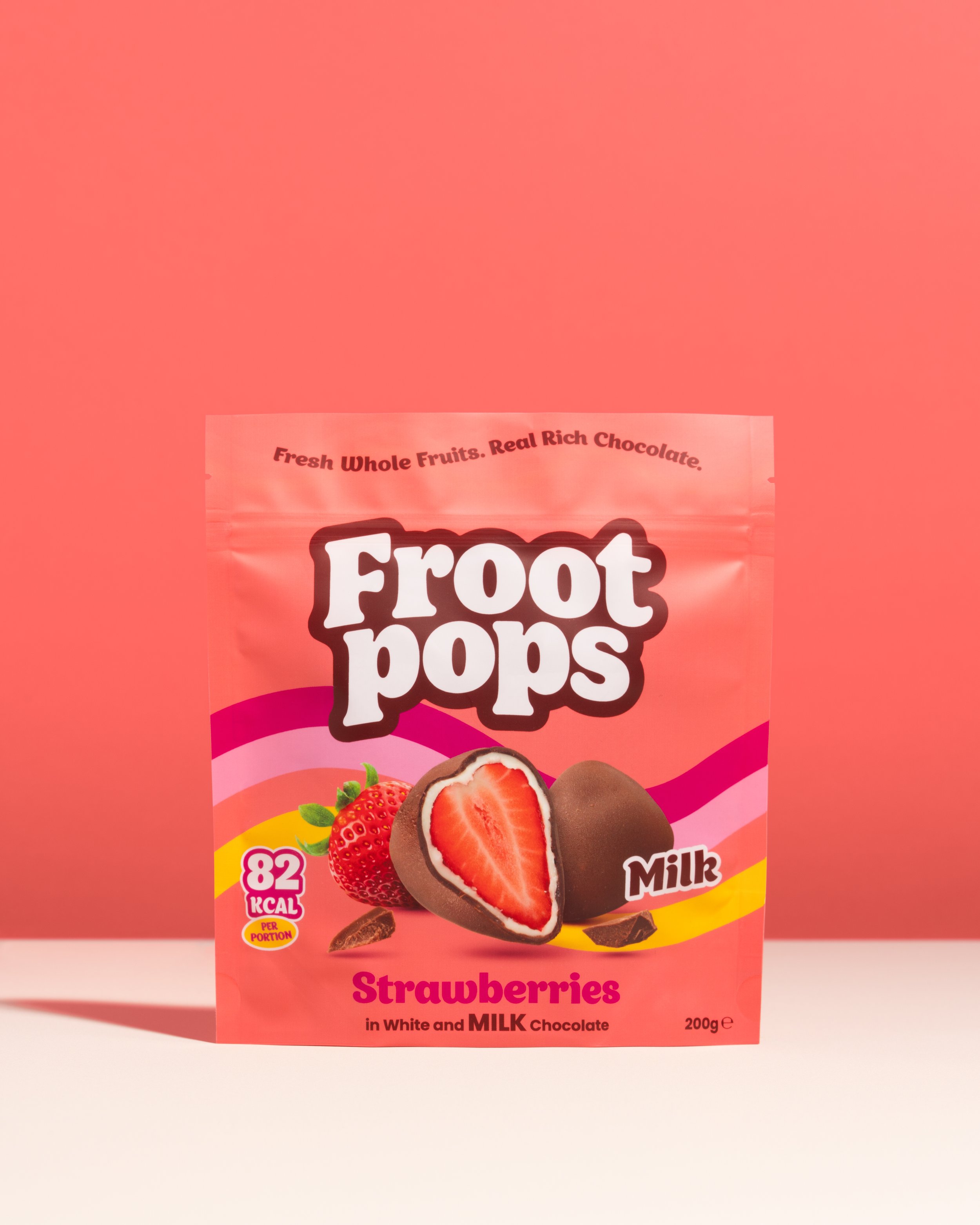A pink package of Froot Pops strawberry ice pops, featuring images of strawberries and chocolate, with nutritional information indicating 82 calories per portion, containing white and milk chocolate, with a net weight of 200 grams.