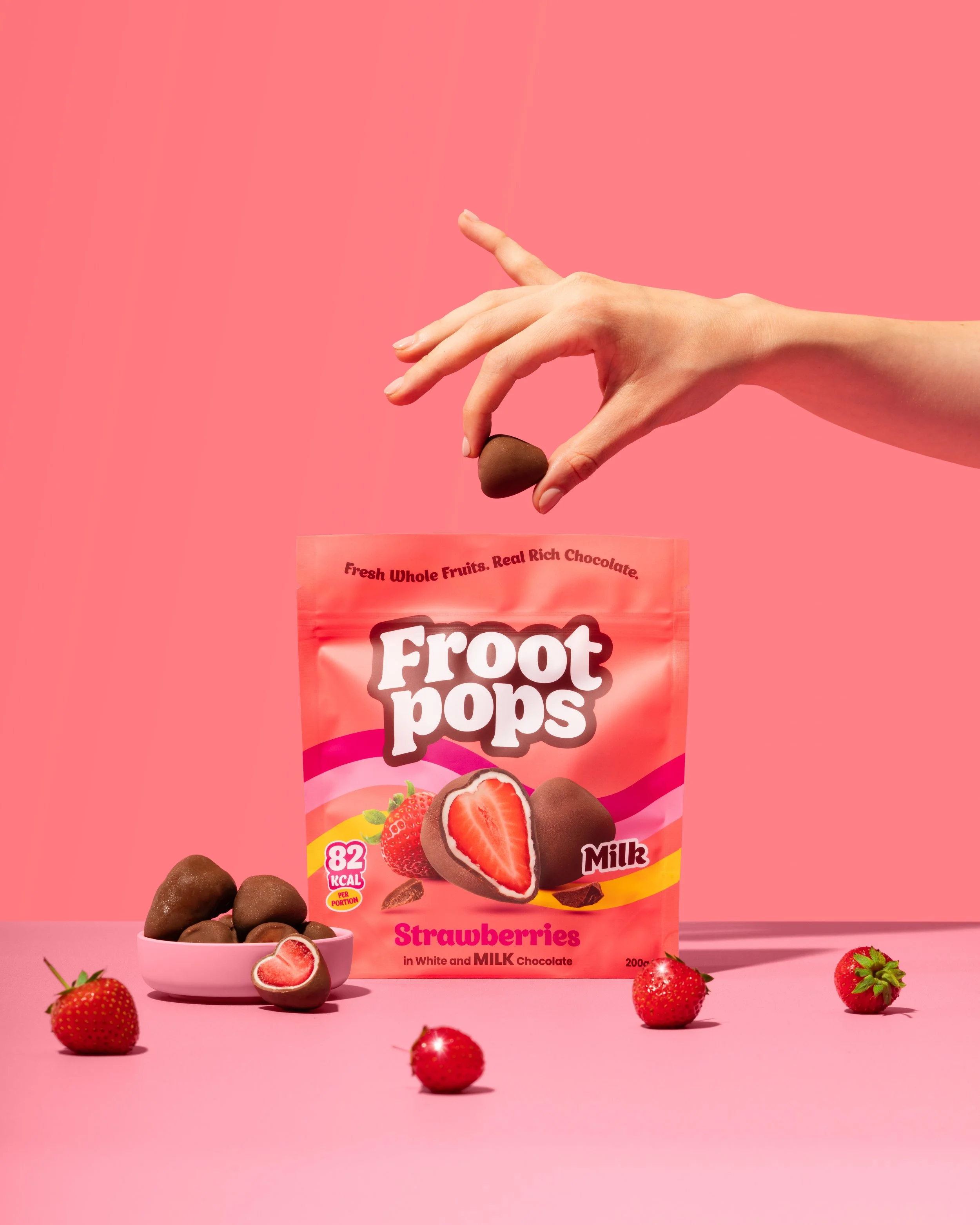 Hand picking up a chocolate covered strawberry from a Froot Pops pouch