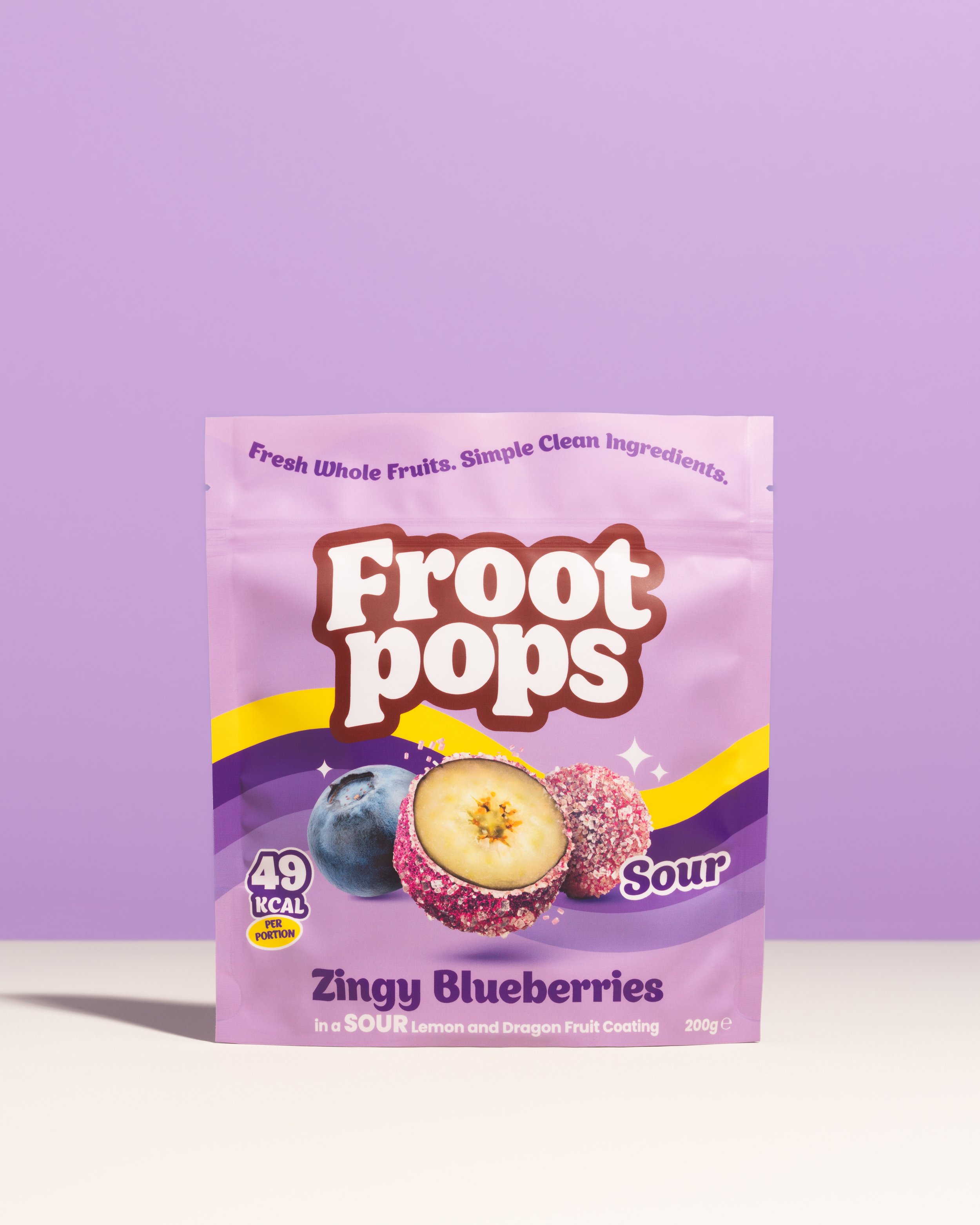 A purple package of fruit pops labeled Zingy Blueberries with an image of blueberries and a blueberry-covered fruit, indicating it is a sour lemon and dragon fruit coated popsicle, containing 49 calories per portion.