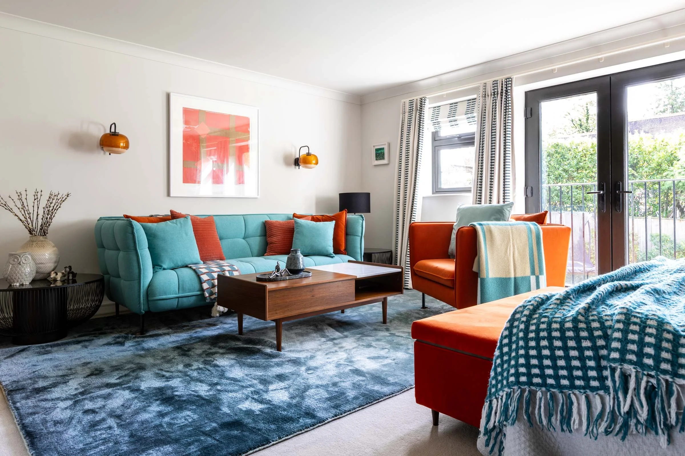 Light teal deep button sofa adn orange chair as a seating area in a master bedroom