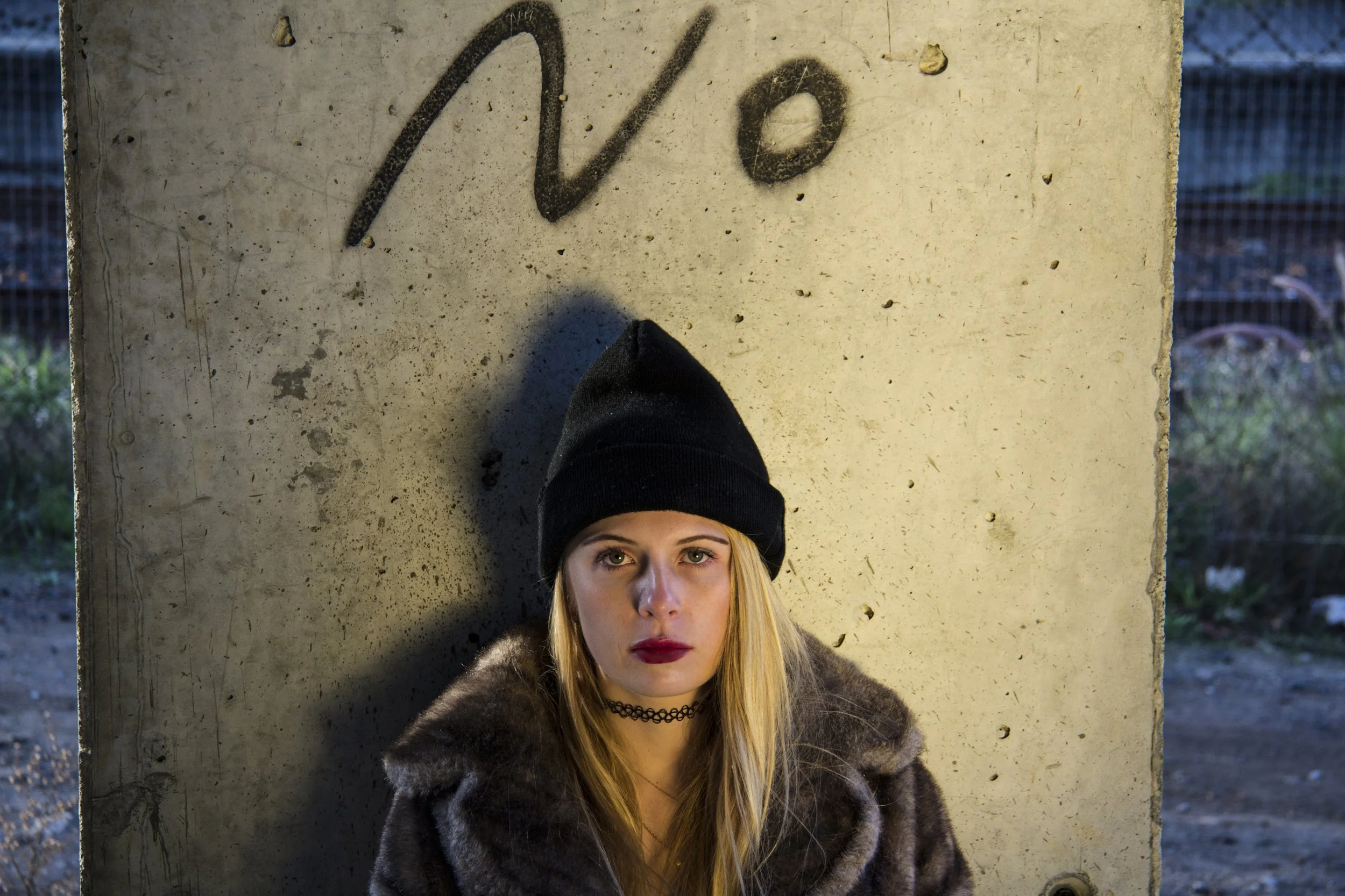 Person leaning against a concrete wall with 'No' graffiti, symbolizing trauma recovery, setting boundaries, and healing through EMDR therapy