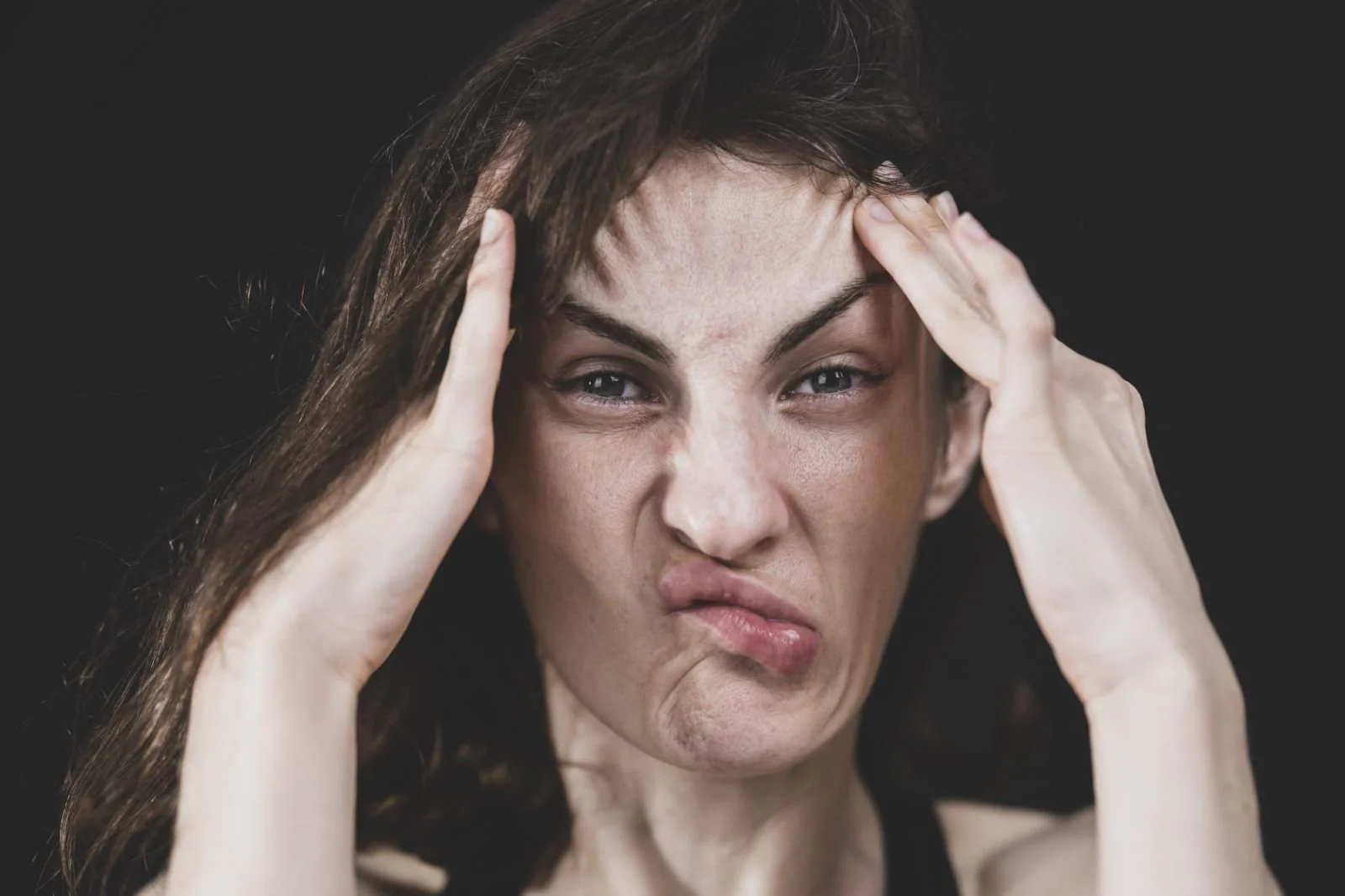 Person holding their head with a distressed expression, illustrating PTSD symptoms and chronic hypervigilance, highlighting how EMDR therapy helps process trauma and reduce constant alertness.