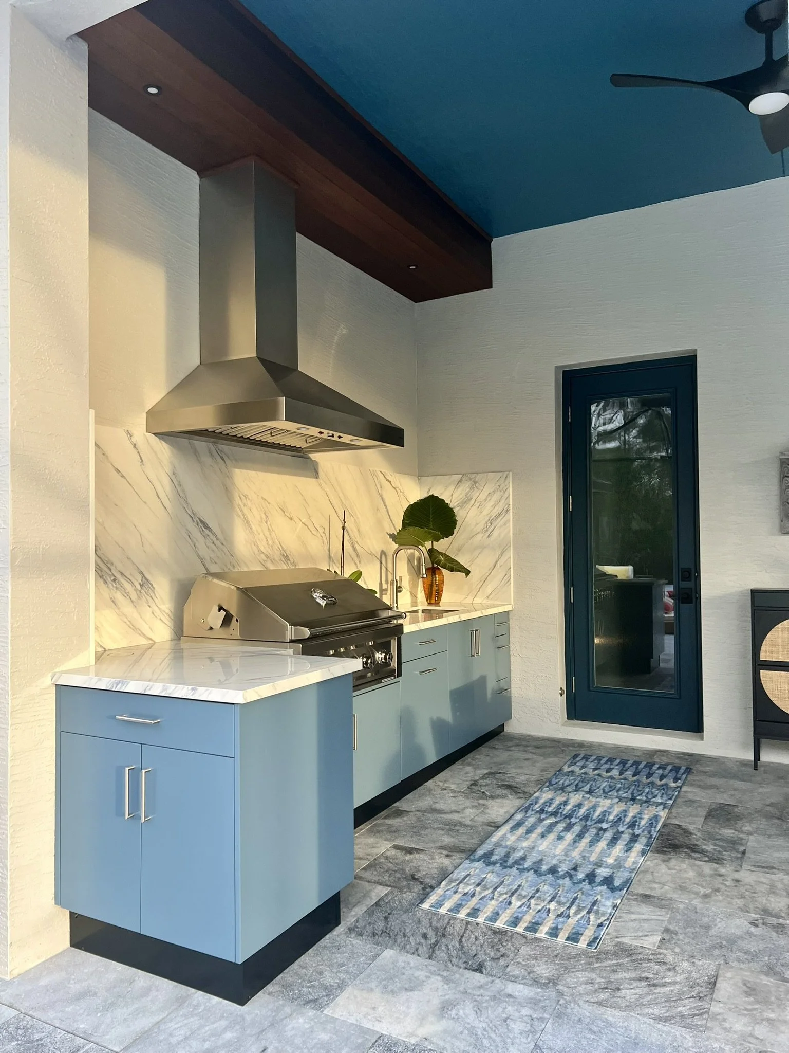 Danver powder-coated stainless steel cabinetry in Military Blue with Dekton "Trance" polished Porcelain Slab top and backsplash, Sunstone Grill, Coyote 42" Fan, ventilated through a  solid Ipe wood covered soffit.