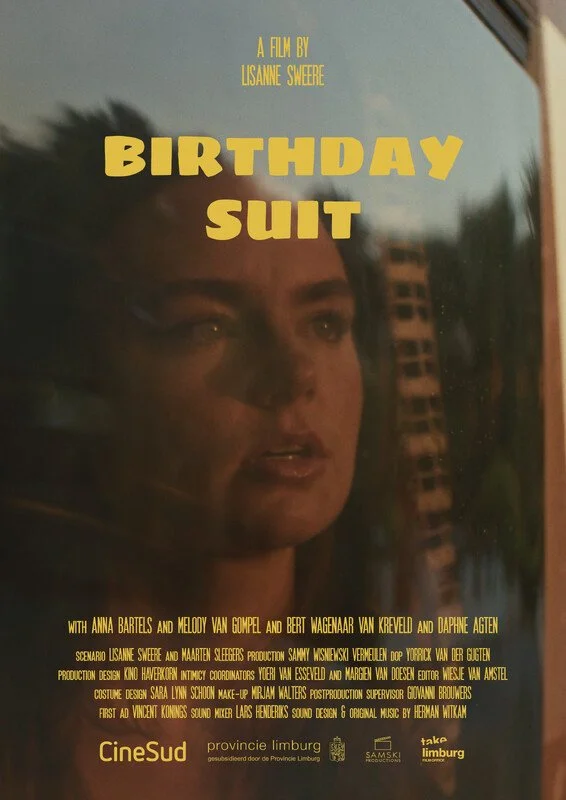 Movie poster for 'Birthday Suit' featuring a woman's face looking out a window with a cityscape reflected. Title in large yellow letters, with credits and logos at the bottom.
