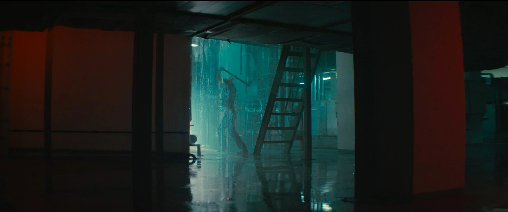 Indoor car wash with water spraying and a person cleaning a vehicle.