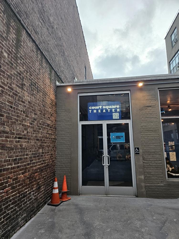 Entrance to the Count Square Theater with two orange traffic cones outside and a blue sign above the door.