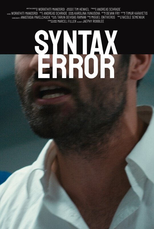 Close-up of a man with facial hair wearing a white collared shirt, with the title 'Syntax Error' in bold white and black text above him. The background is blurred.