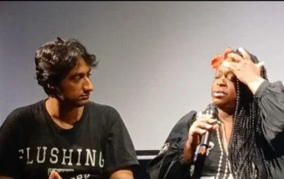 Two women engaged in a conversation, one is holding a microphone and appears emotional, the other looks on attentively.