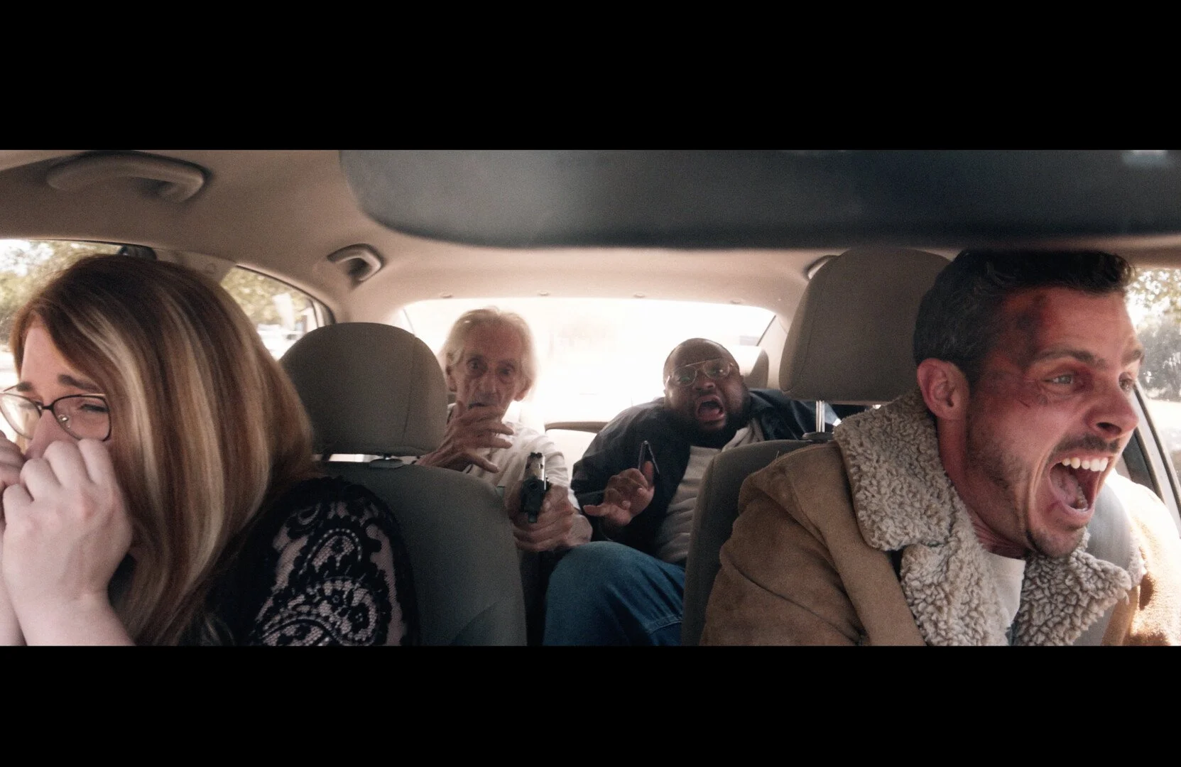 People in a car experiencing a dangerous situation, with a woman crying, an elderly man with a gun, a man shocked and holding a phone, and a man driving and screaming.