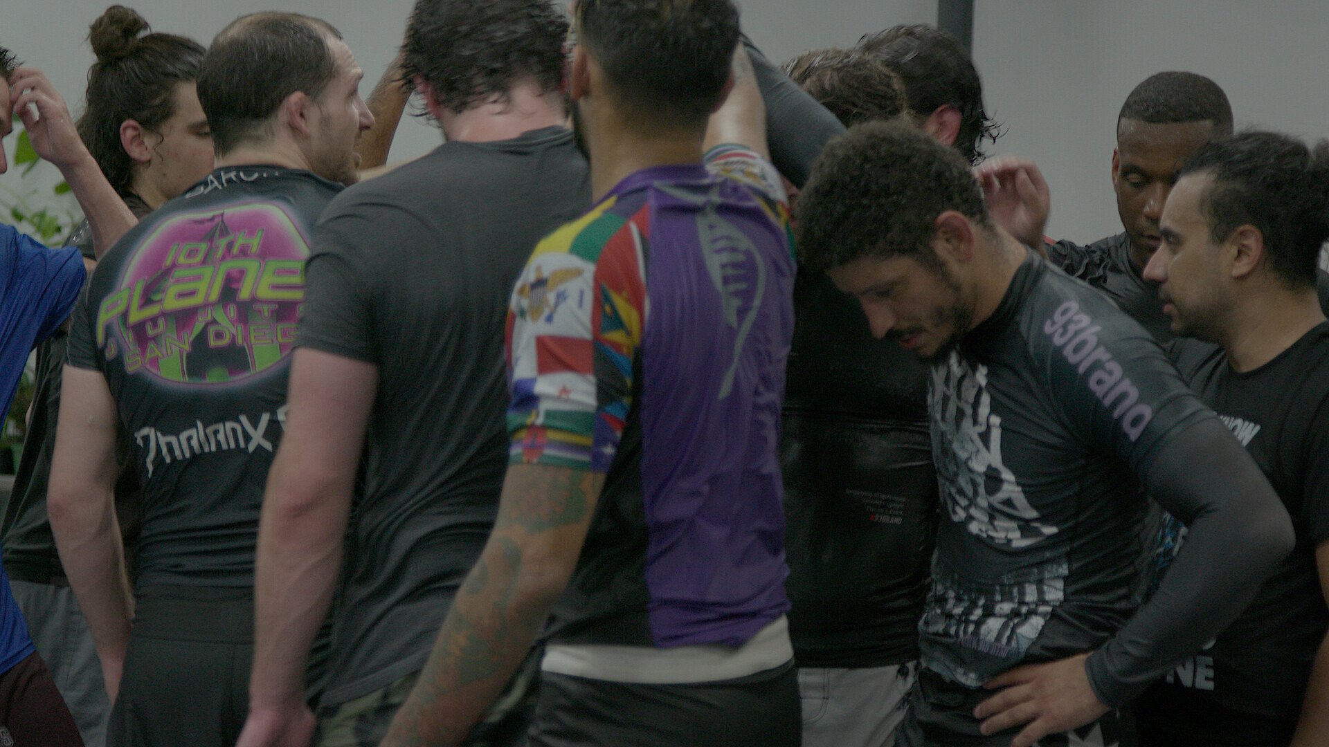 A group of people gathered closely together, some with their heads bowed, appearing to be in a moment of reflection or prayer.