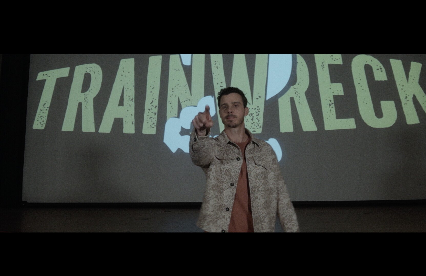 A man stands on stage in front of a screen with the