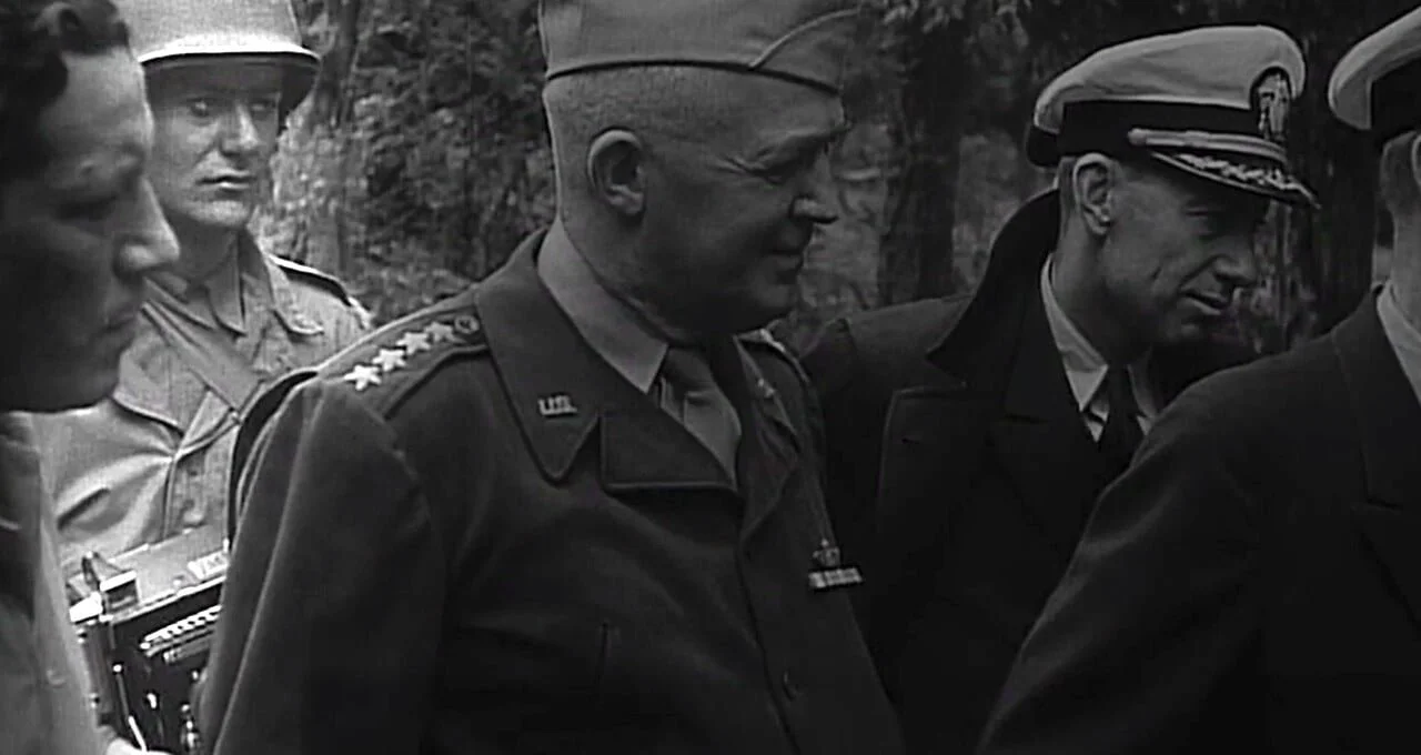 Black and white photo of military and military-adjacent men in uniform, some wearing hats, standing outdoors.