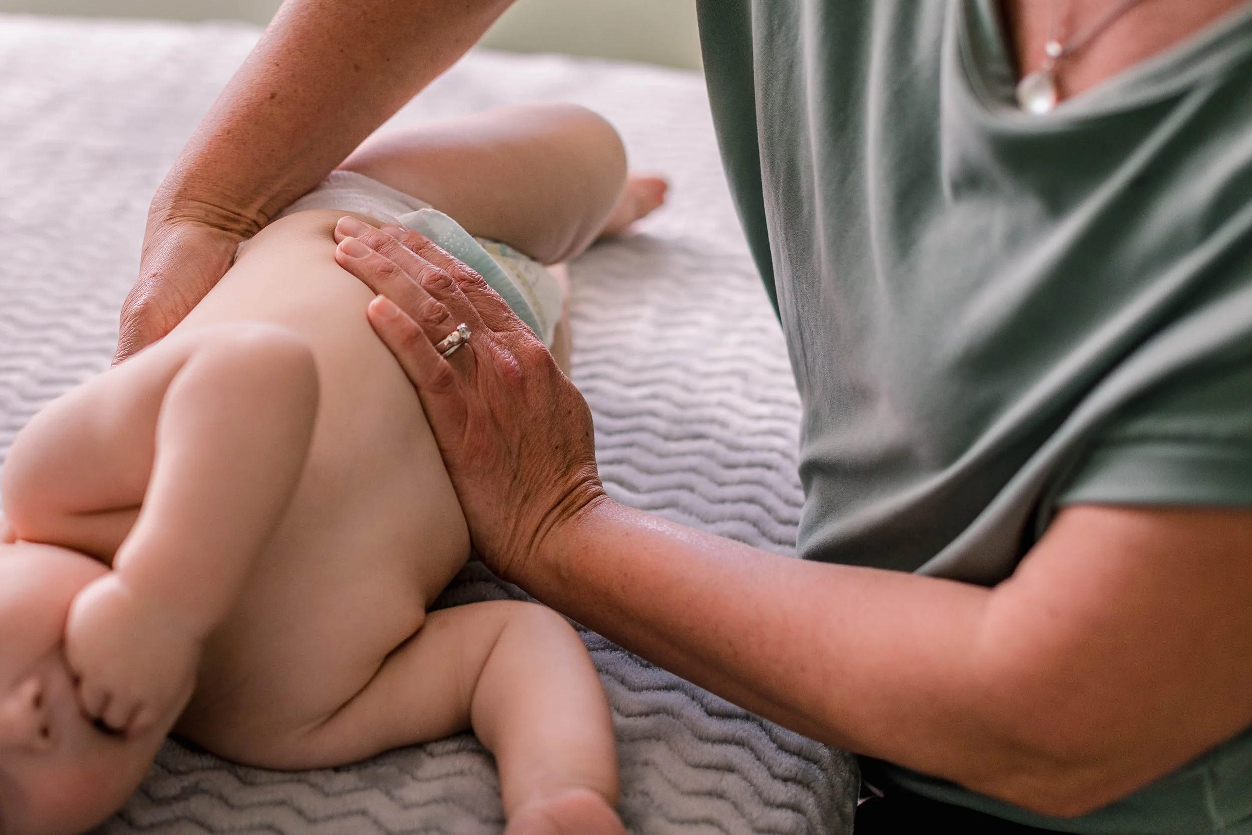 Closeup of a myofascial release practitioner doing a maneuver on the stomach of an infant