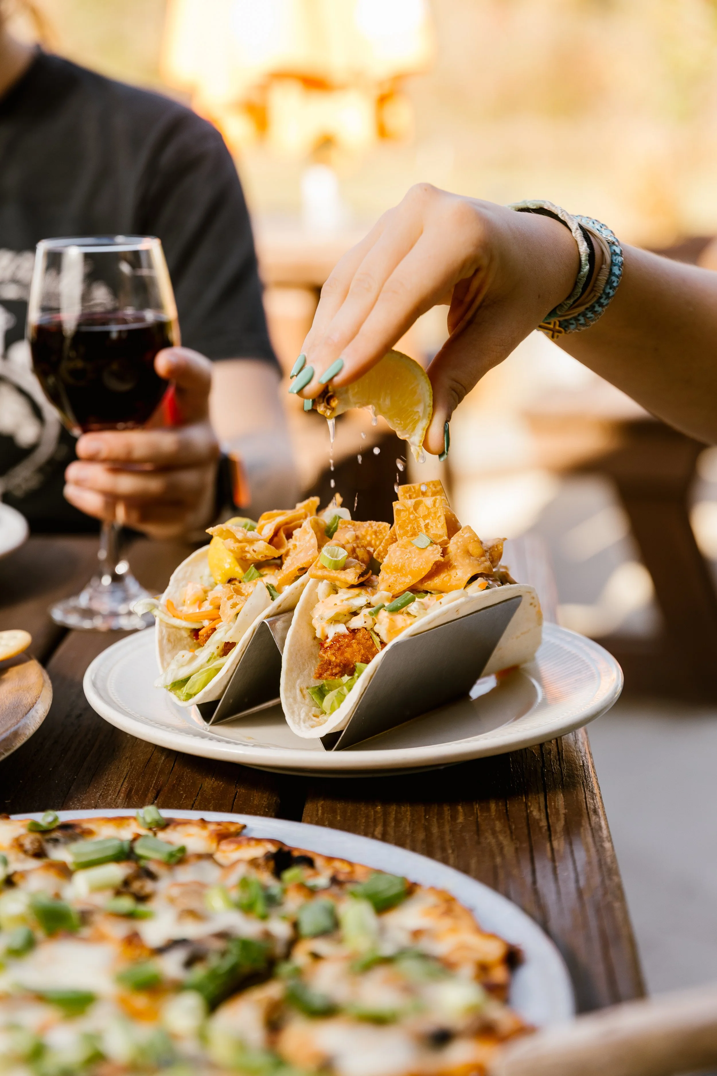 A women squeezin lemon juice over two walleye tacos