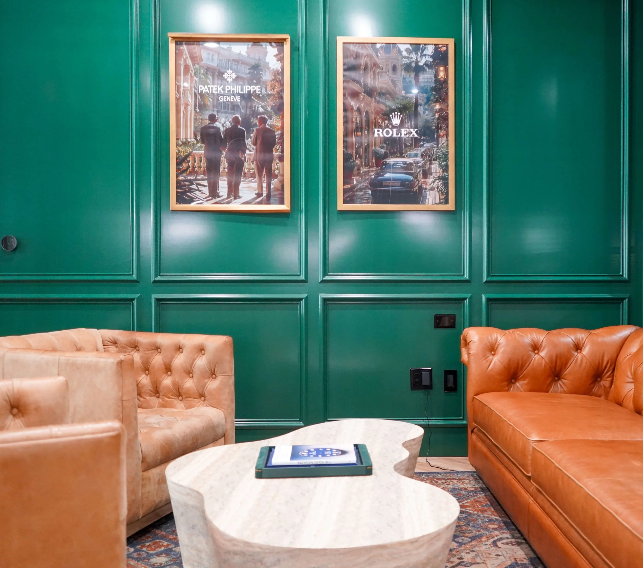 Patek Philippe and Rolex prints above tan leather chesterfield seating at The Crown Houston
