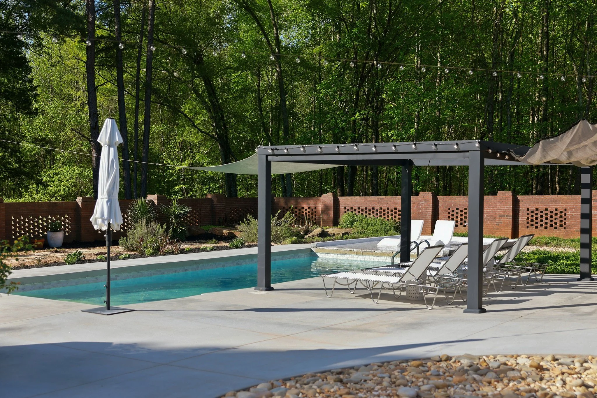 The sprawling pool deck sits gracefully in front of a backdrop of native woods
