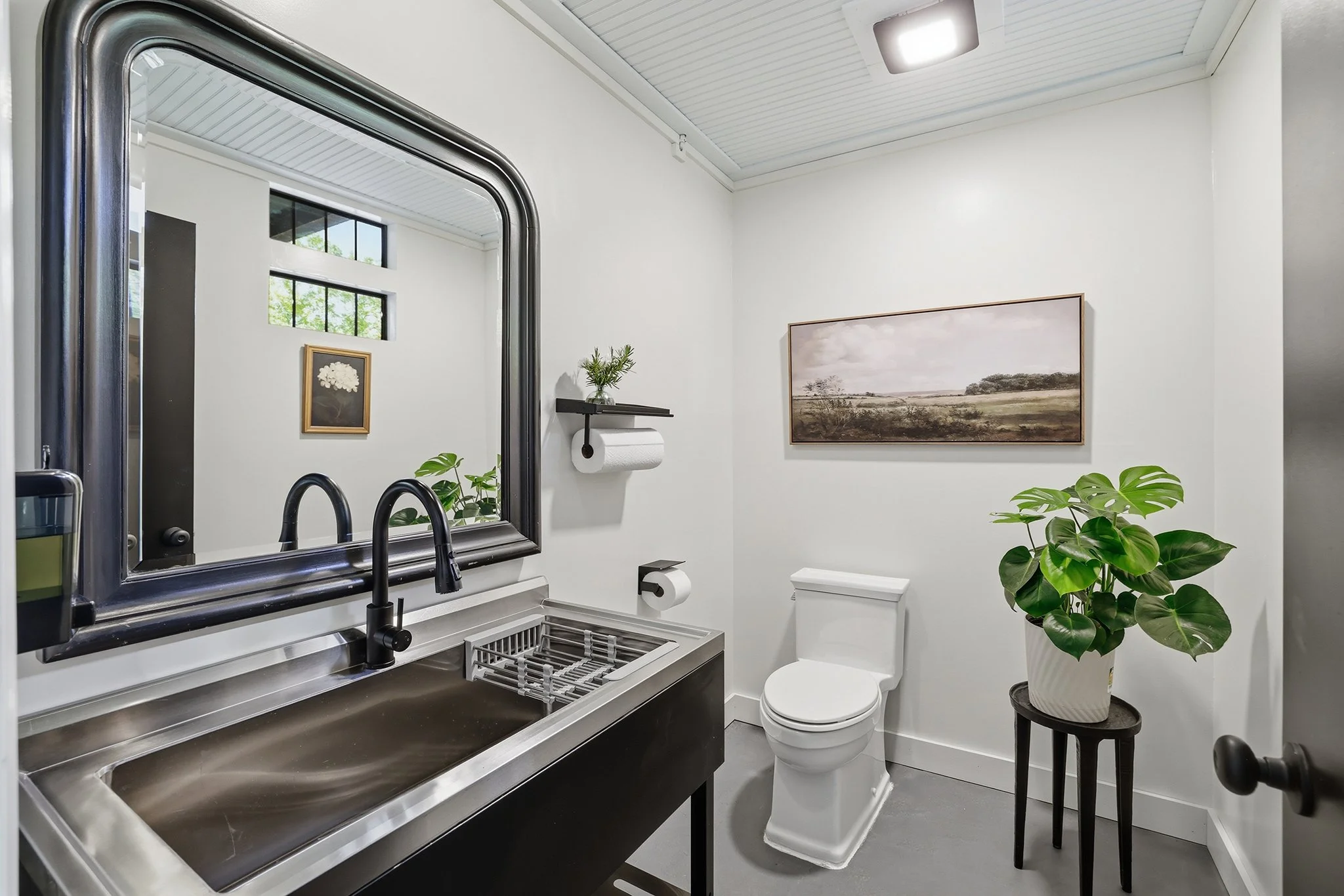 Newly renovated half-bath with a deep stand-alone utility sink for hands and brushes, plus transom windows for abundant natural light, is quite charming