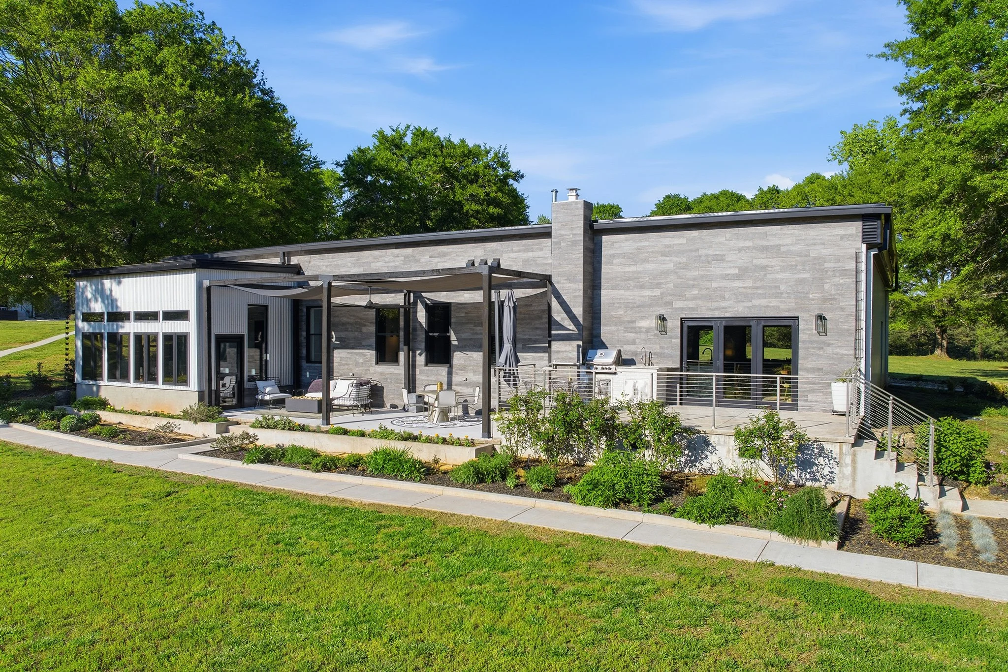 Midday view of the back of the home with raised flower beds under bright sun and blue skies — pure Southern perfection