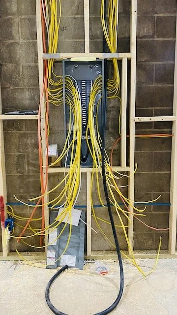 Electrical wiring with yellow, orange, and black cables in a wall frame, connected to a metal junction box.