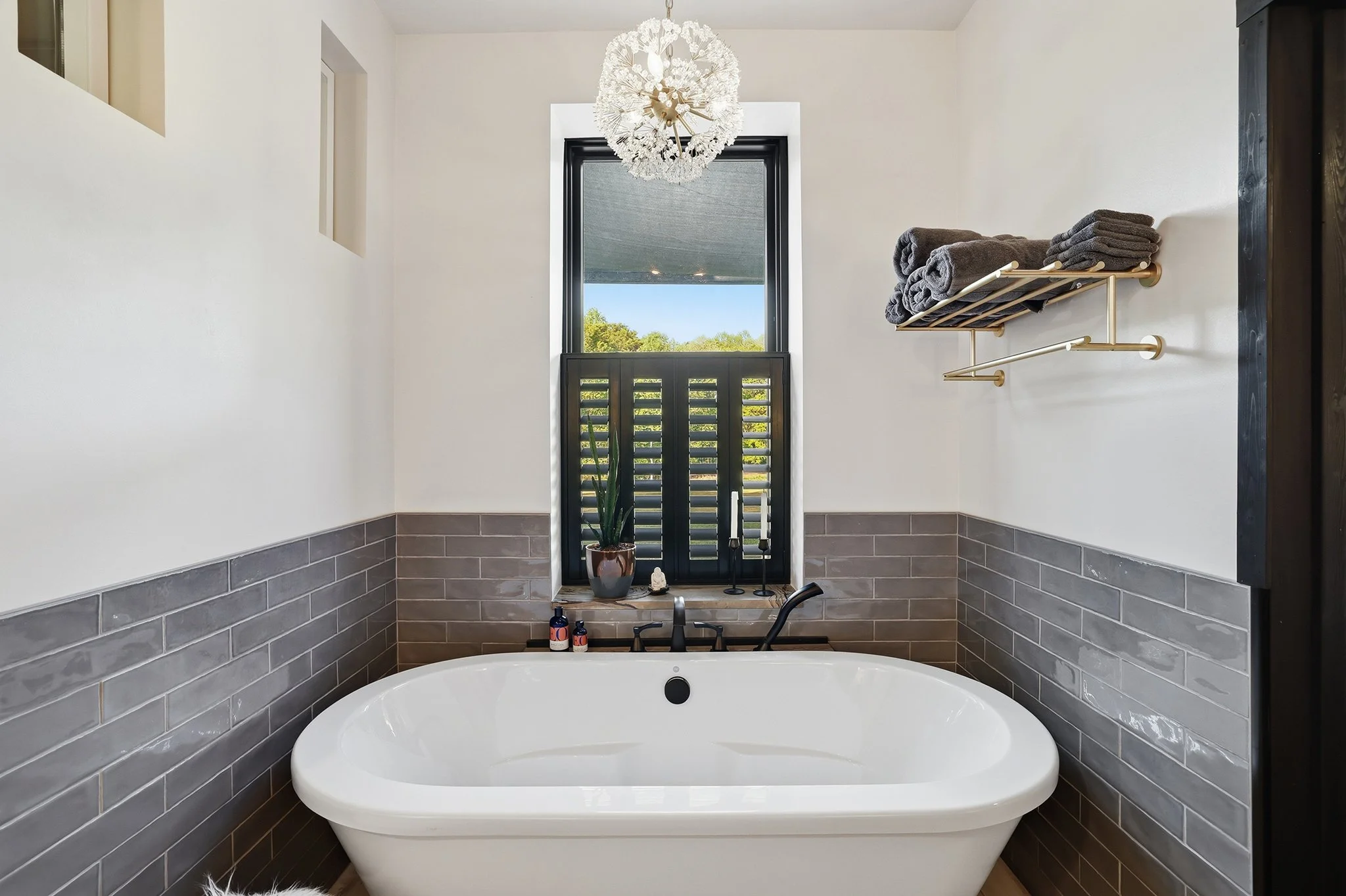 Unwind in luxury with the deep soaking tub, chandelier, and ebony Charleston shutters