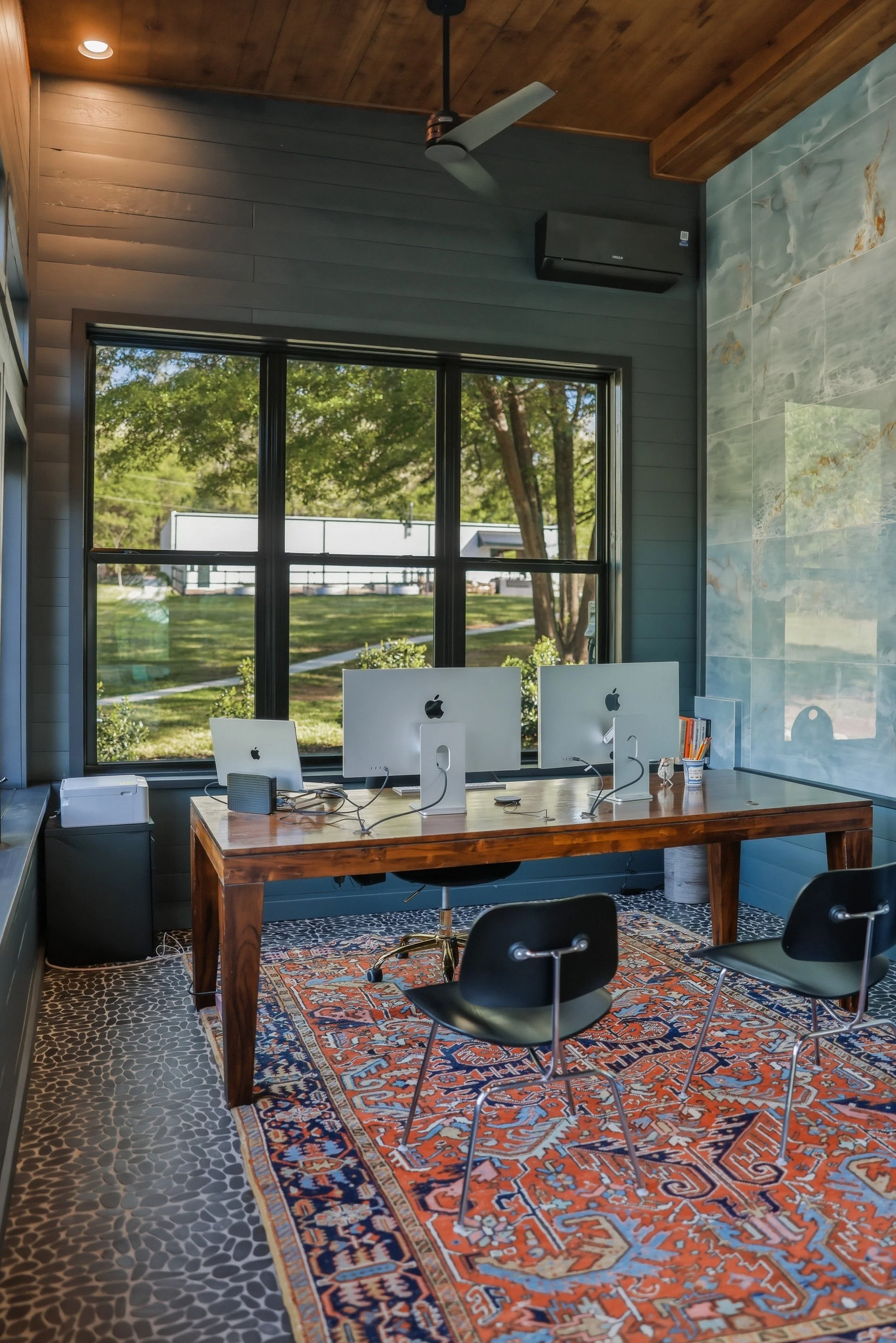 The four-season room features generous windows throughout, shiplap walls, tiled accent wall, stone floor, and its own mini-split