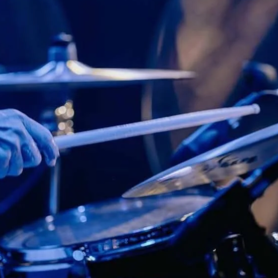 Close-up of a drummer playing a drum kit, holding a drumstick over a snare drum