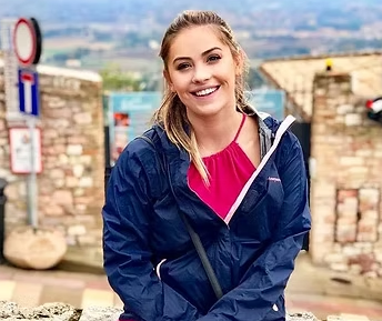 Emily Garven smiling outdoors, wearing a pink top and navy jacket.