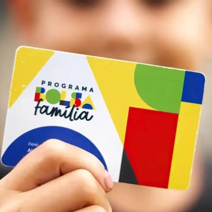 Cartão do Programa Bolsa Família sendo segurado por uma pessoa.