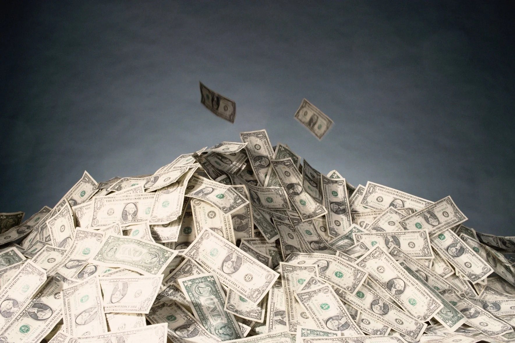 pilhas de dinheiro de papel de cem dólares sendo despejadas em uma pilha.