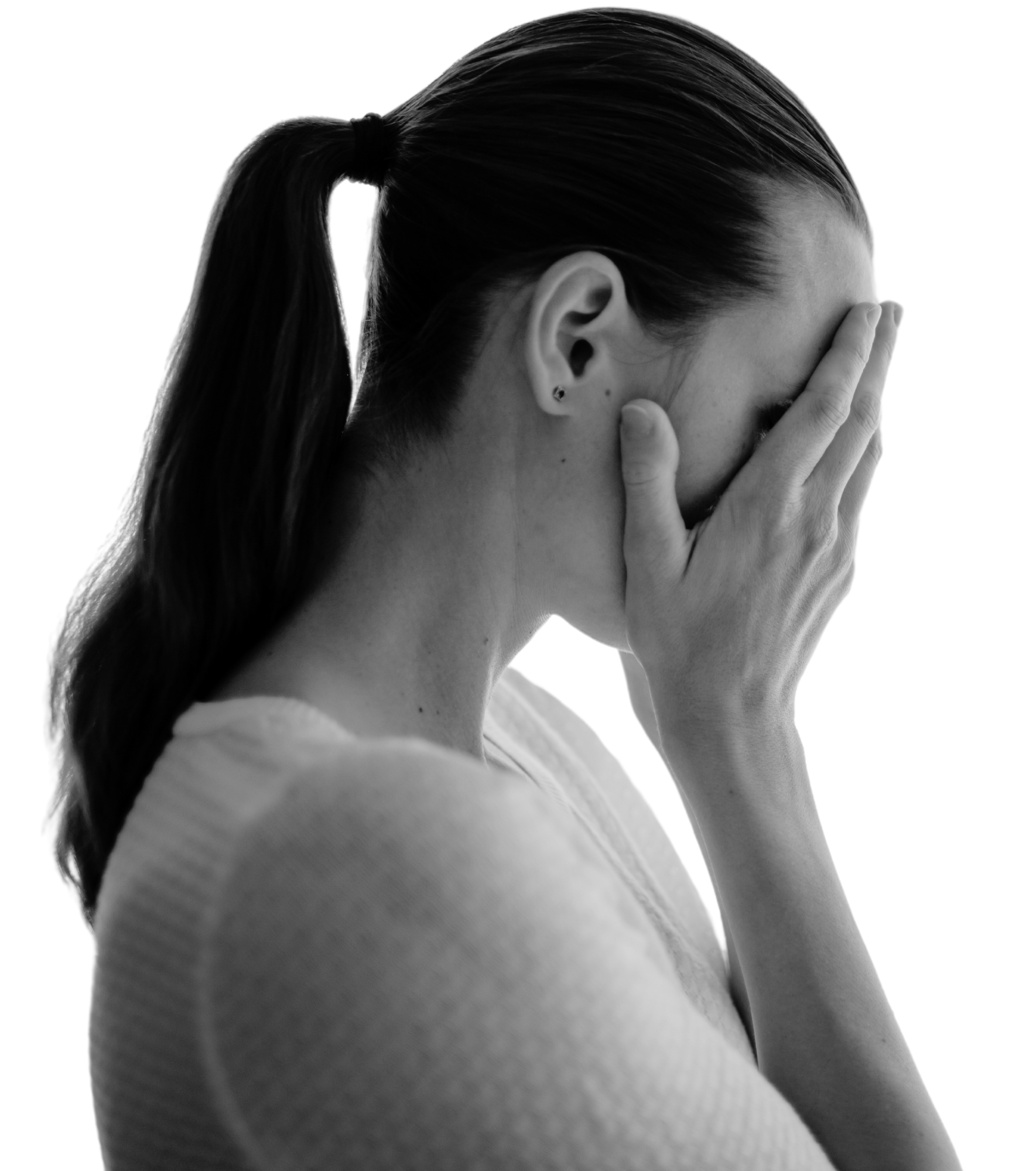 Mulher aparente estar angustiada ou preocupada, com as mãos cobrindo o rosto, em uma expressão de dor ou tristeza, em uma imagem em preto e branco.