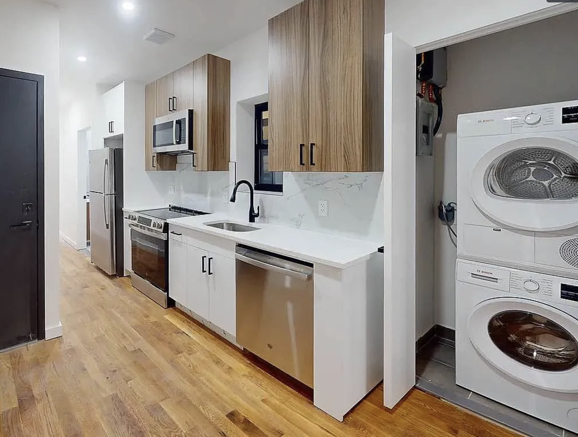 Modern kitchen with wooden cabinets, white marble backsplash, stainless steel appliances, and a laundry area with stacked washer and dryer.