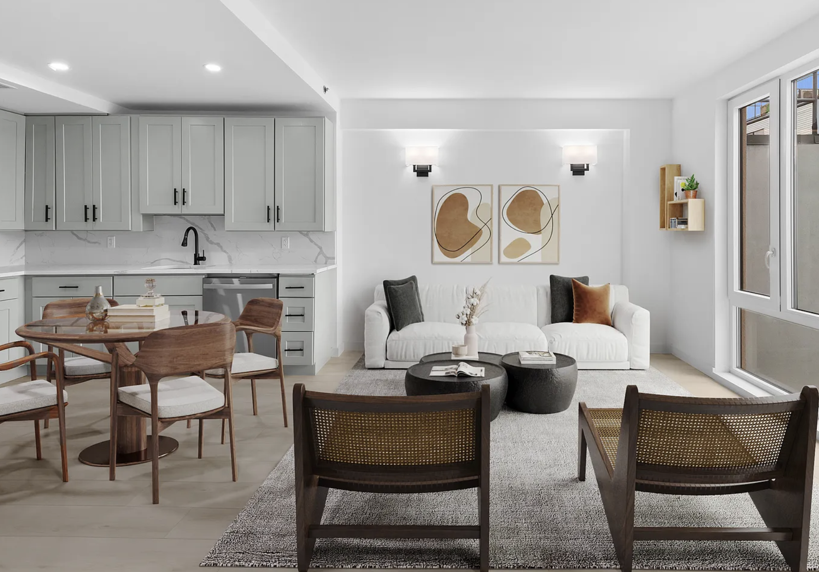 Open-concept living room and kitchen with white walls, gray cabinets, black hardware, a white sofa with dark gray and brown pillows, modern wall art, a wooden dining table with matching chairs, black coffee tables, and large windows bringing in natural light.
