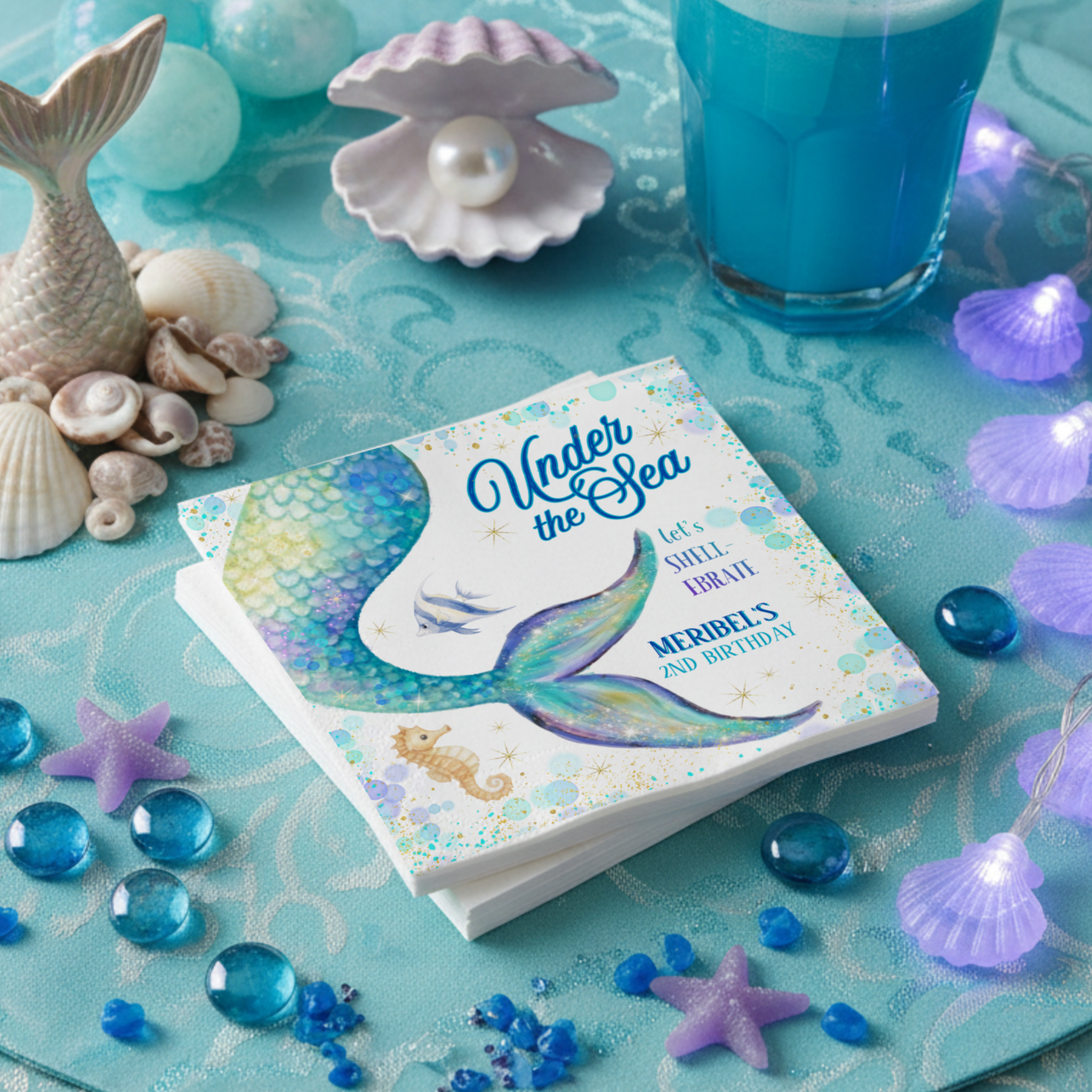 Mermaid Under the Sea birthday napkins featuring a dreamy watercolor mermaid tail, soft teal and sea foam tones, hints of purple, shimmering bubbles, and gold star accents. With sweet ocean details like a seahorse and tropical fish, these napkins add