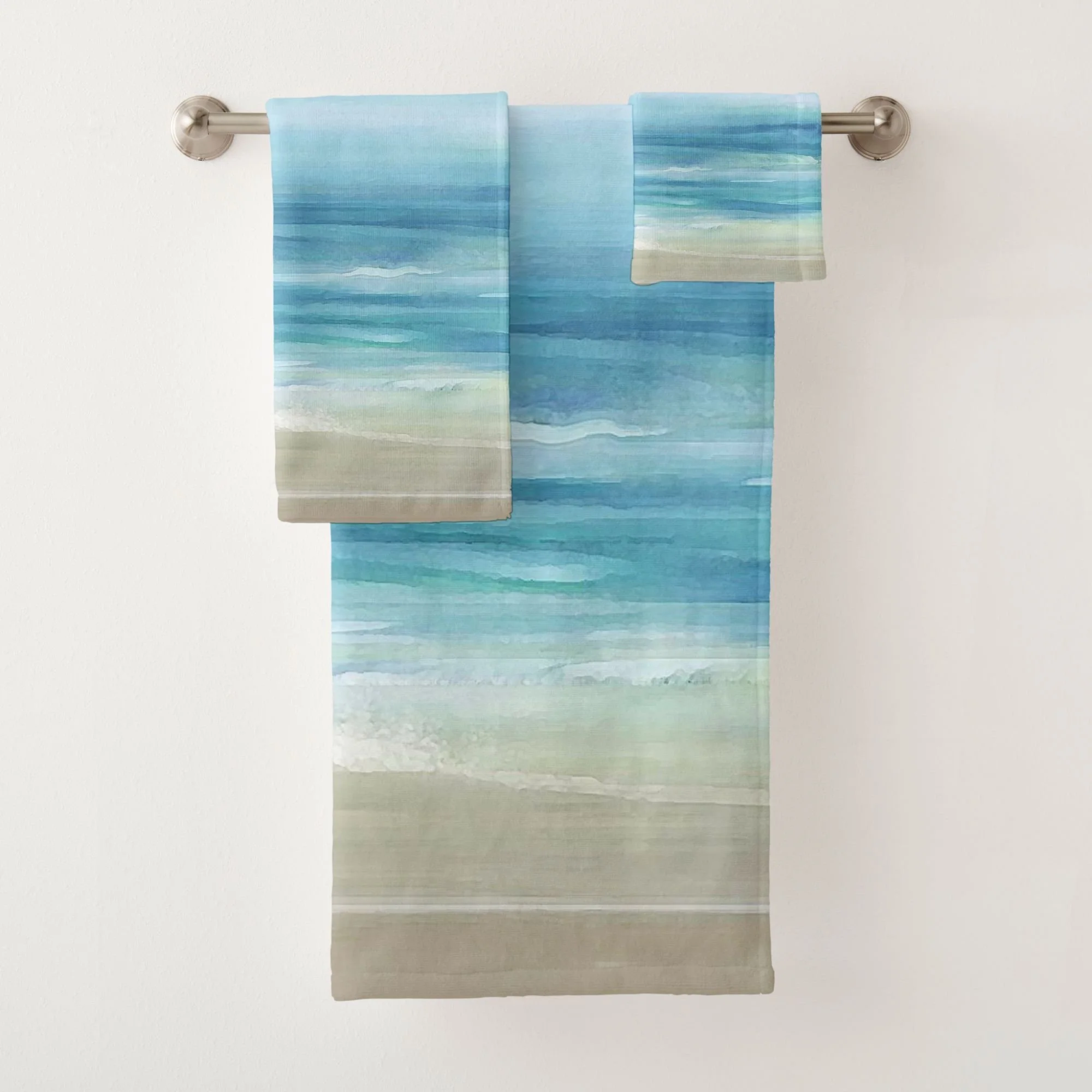Bring a relaxing, serene spa vibe to your bathroom with this coastal bath towel set featuring sea blue watercolor ocean waves and beige sand. Perfect for a beach house and nautical themed decor.