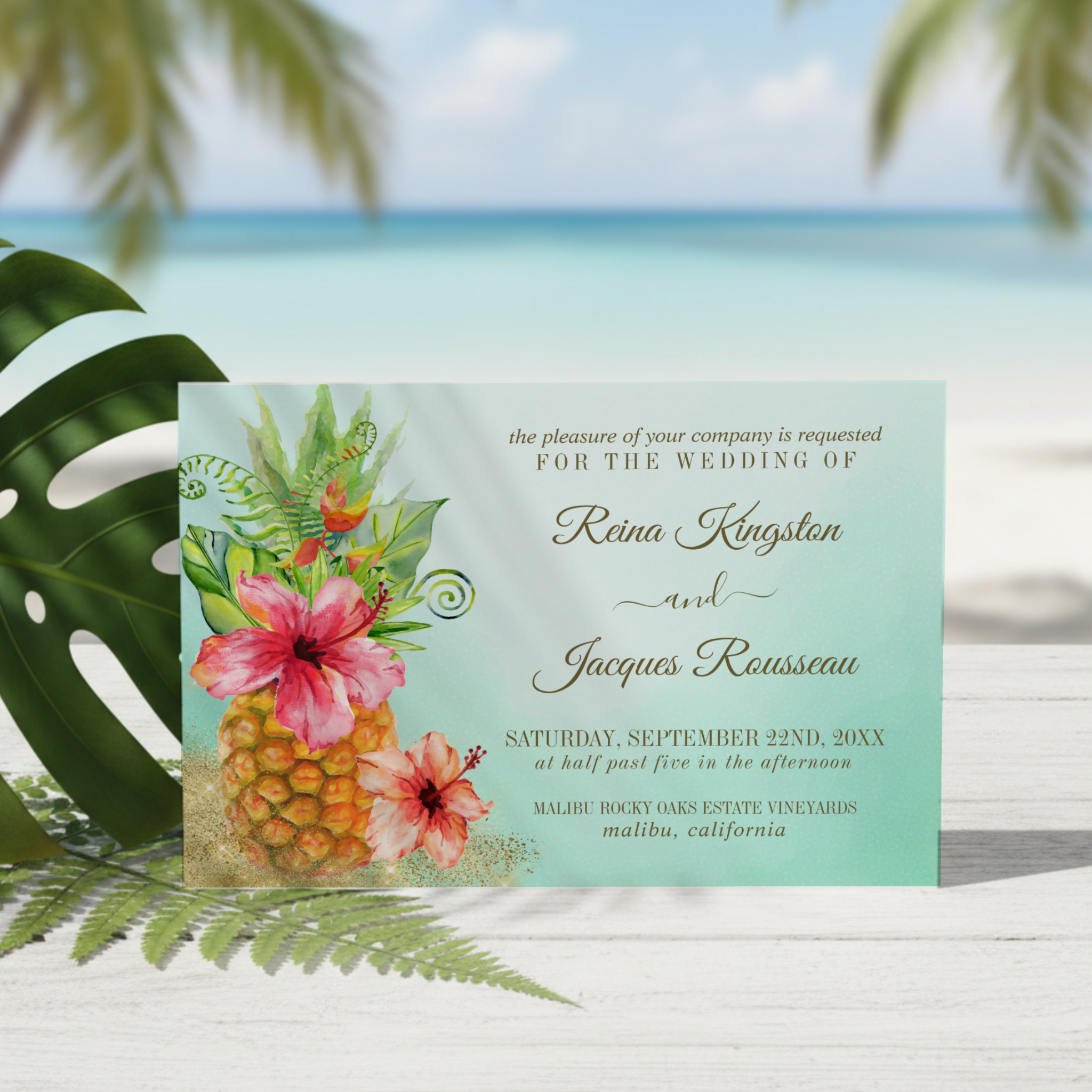 Island inspired wedding invitation featuring a pineapple, hibiscus flowers palm leaves and sparkling gold sand on a soft turquoise watercolor wash background. Perfect for tropical, beach and coastal destination weddings. 