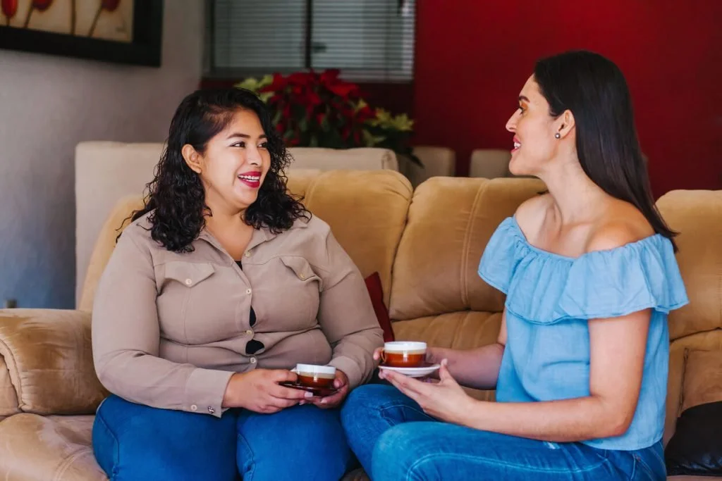 Women sitting together on a couch, enjoying an easy one-on-one conversation.