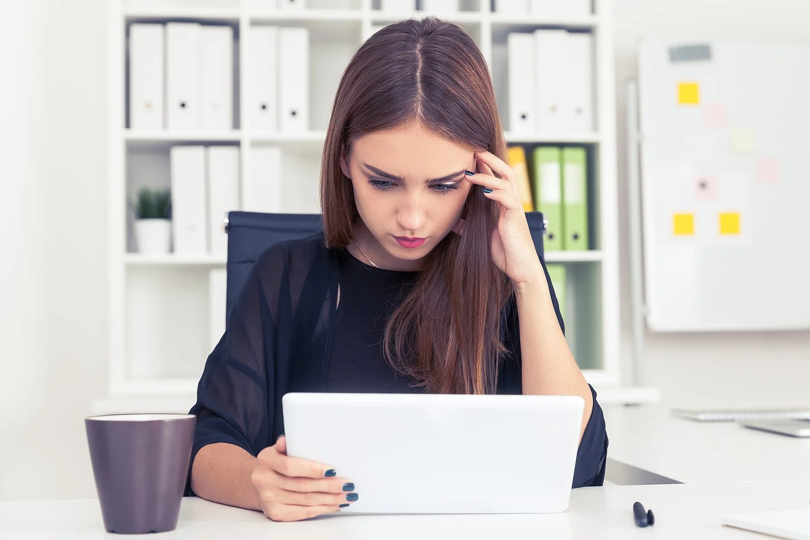 A stressed woman looking at her laptop, overwhelmed by perfectionism.