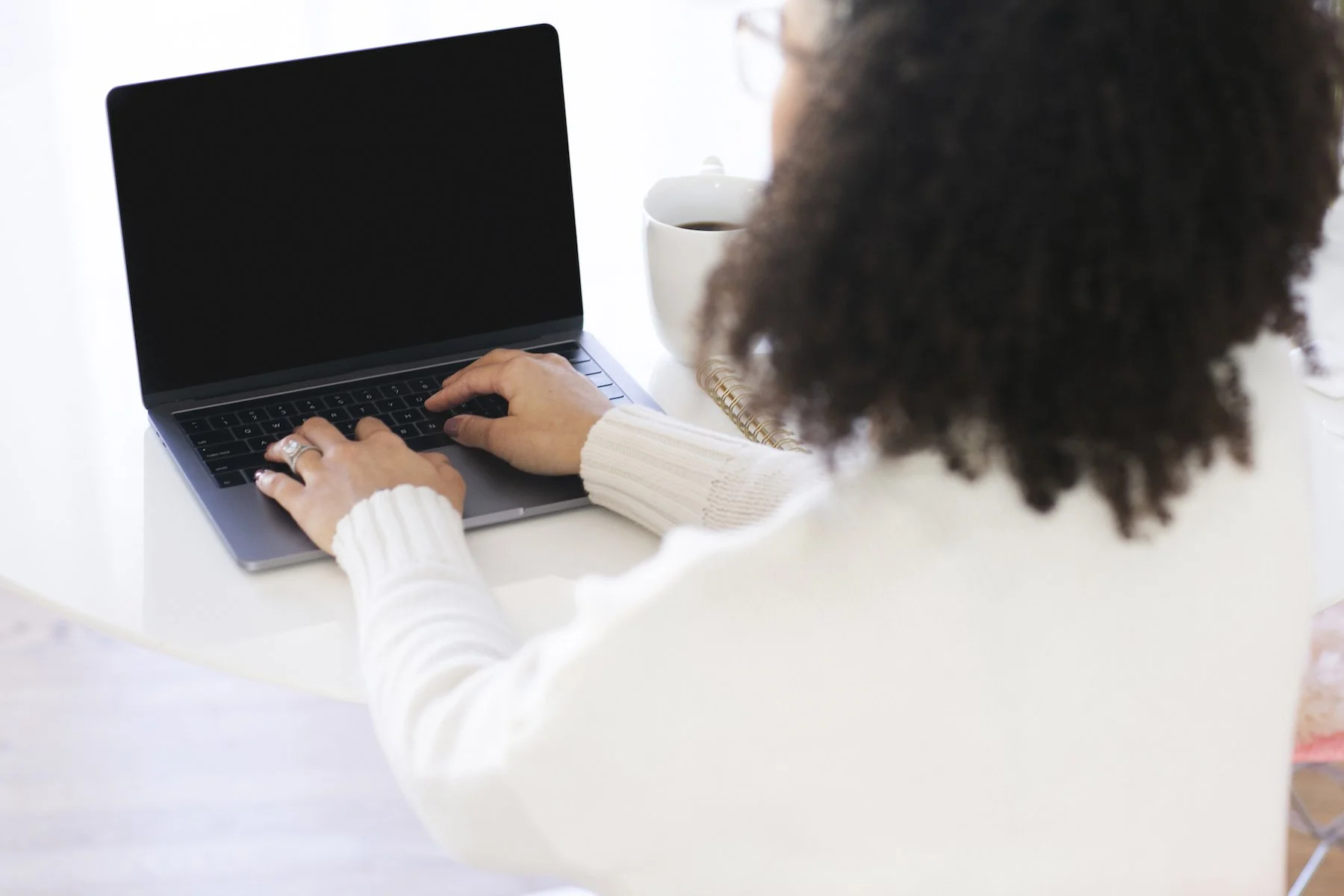 A woman with her back to the camera typing on a laptop.