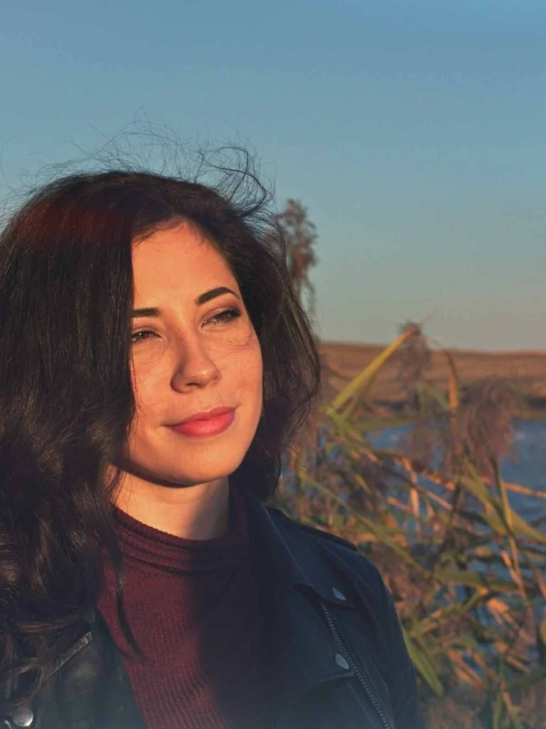 A woman with dark wavy hair looking into the distance in warm evening light, reflecting on being a highly sensitive Latina.